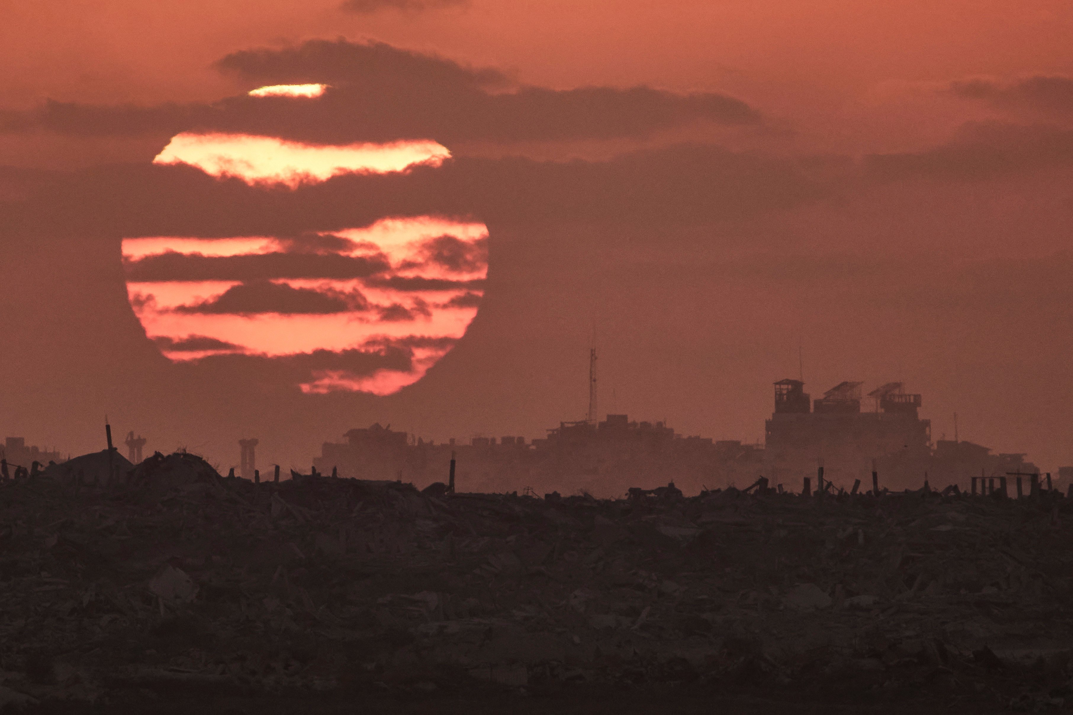 The sun sets on Thursday behind buildings that were destroyed during Israeli ground and air operations in the Gaza Strip. Photo: AP