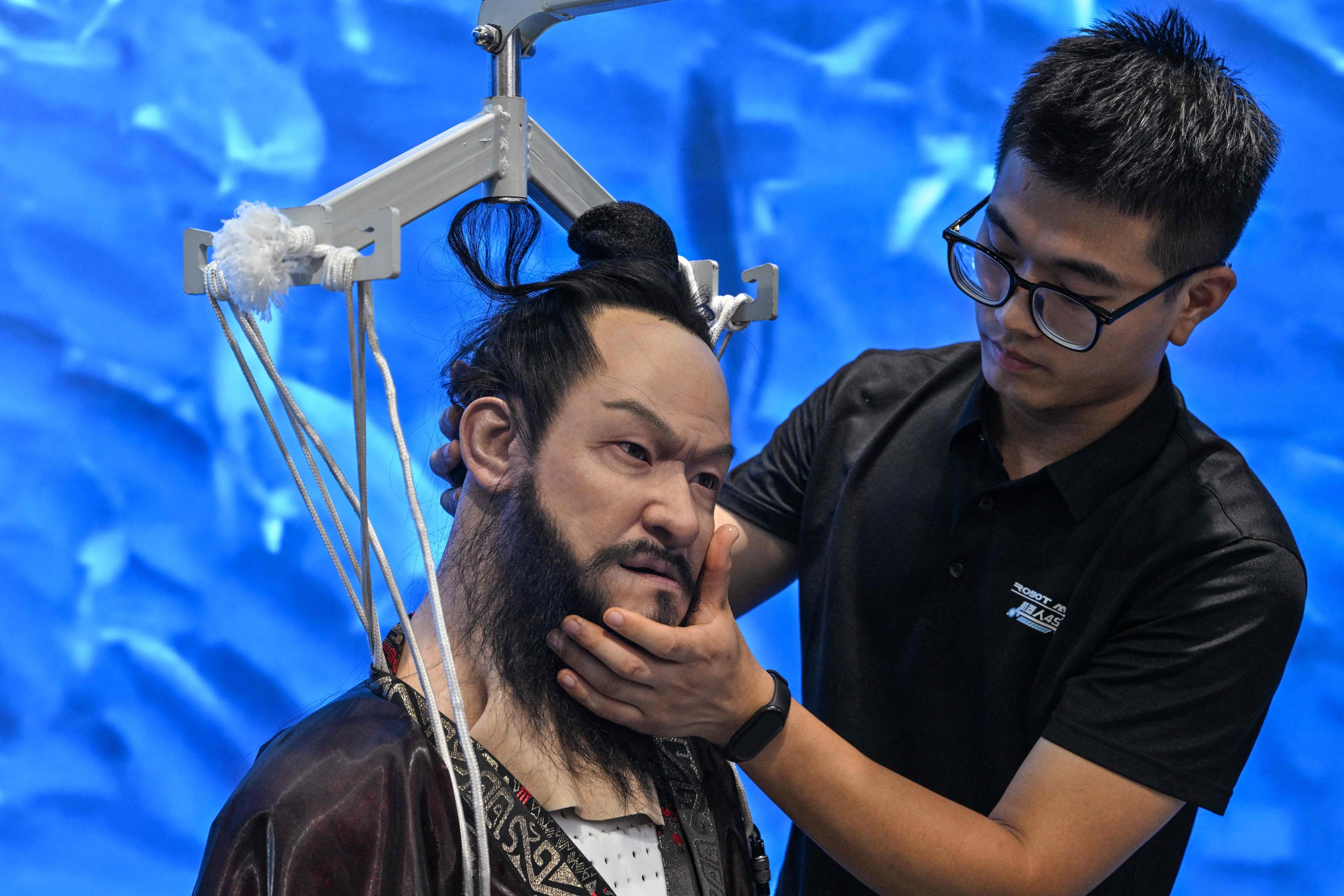A man adjusts a humanoid robot at the Robot Mall in Beijing. Photo: AFP