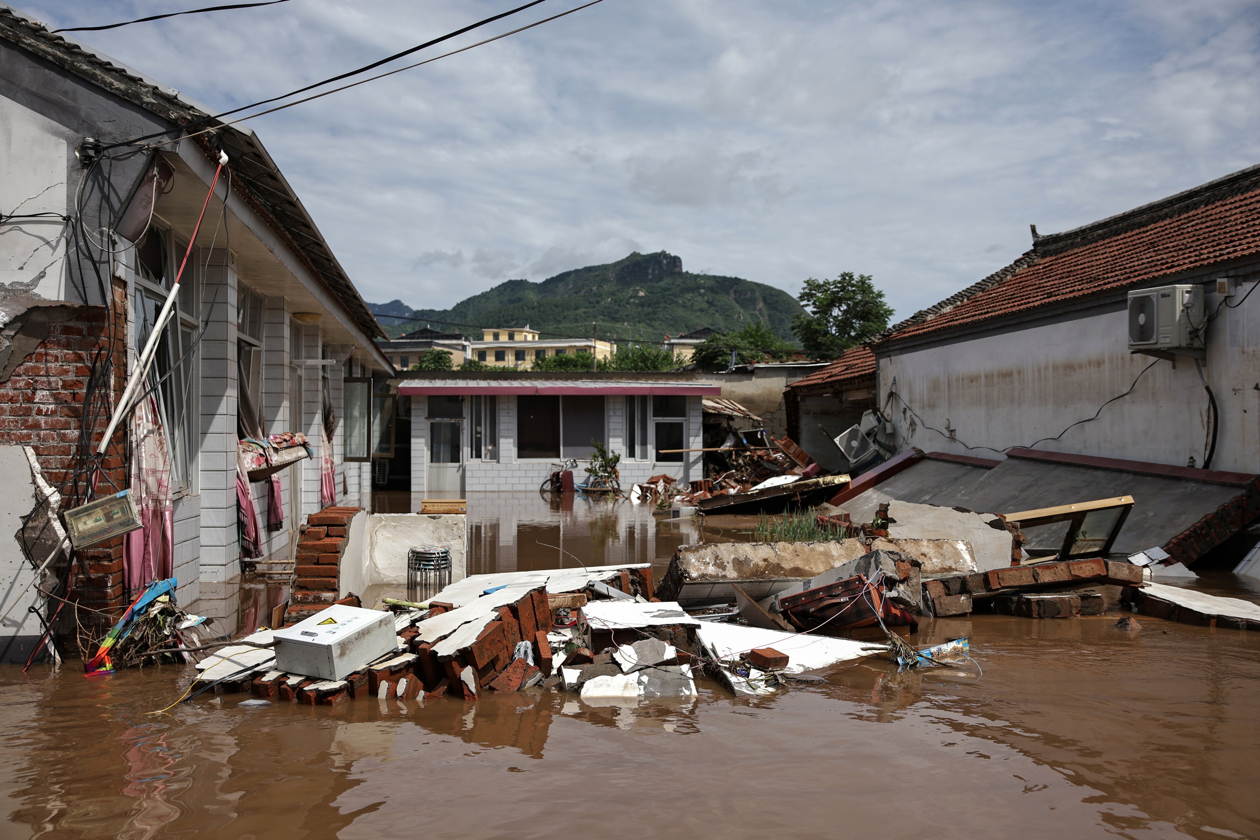 Debris piles up in a flooded street in Taishitun, in Beijing’s Miyun district, late last month.  Photo: EPA