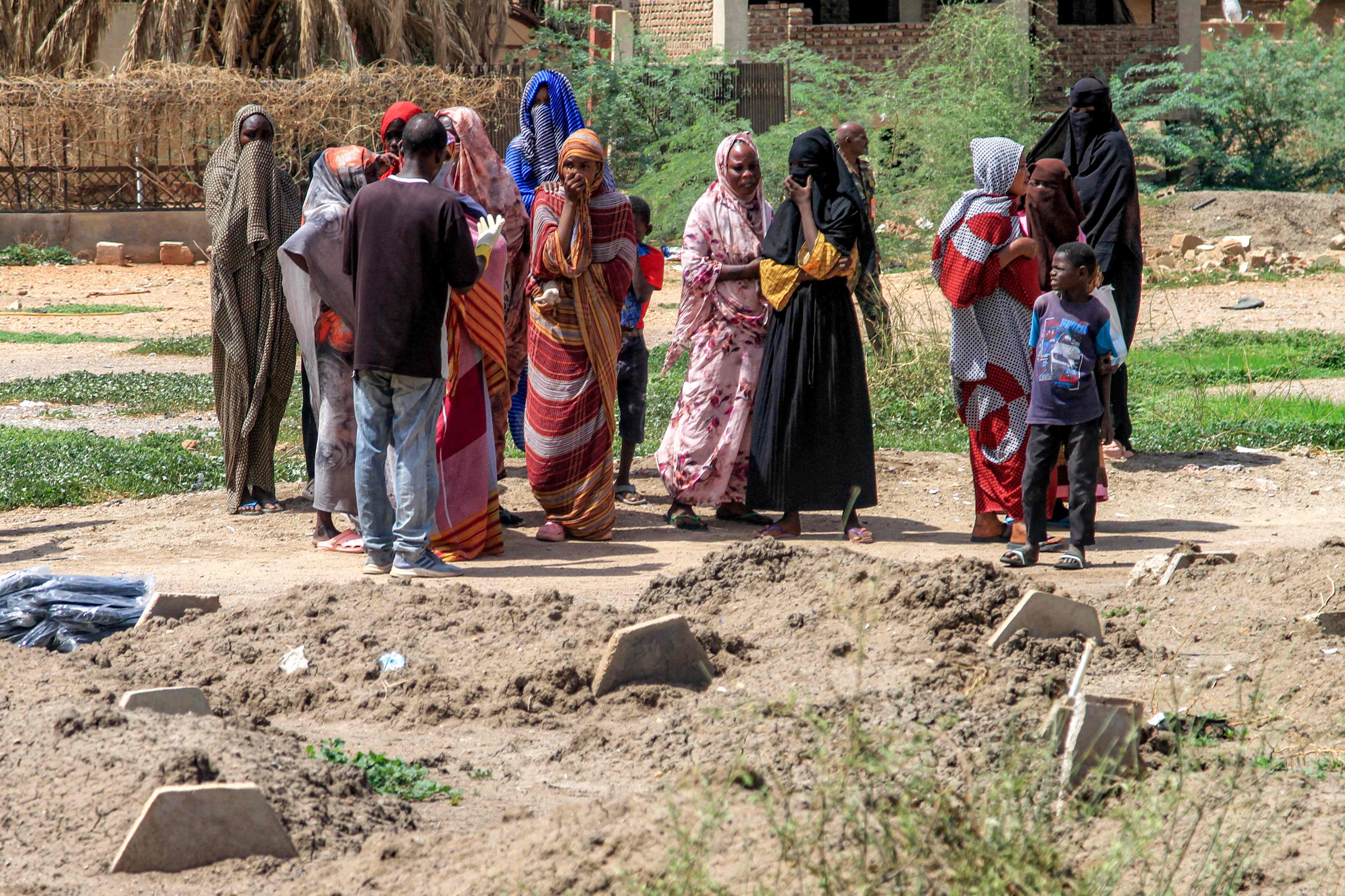 People gather by the makeshift graves of those buried in Khartoum’s southern suburb of al-Azhari on August 2, which will be exhumed for reburial in the local cemetery. Photo: AFP