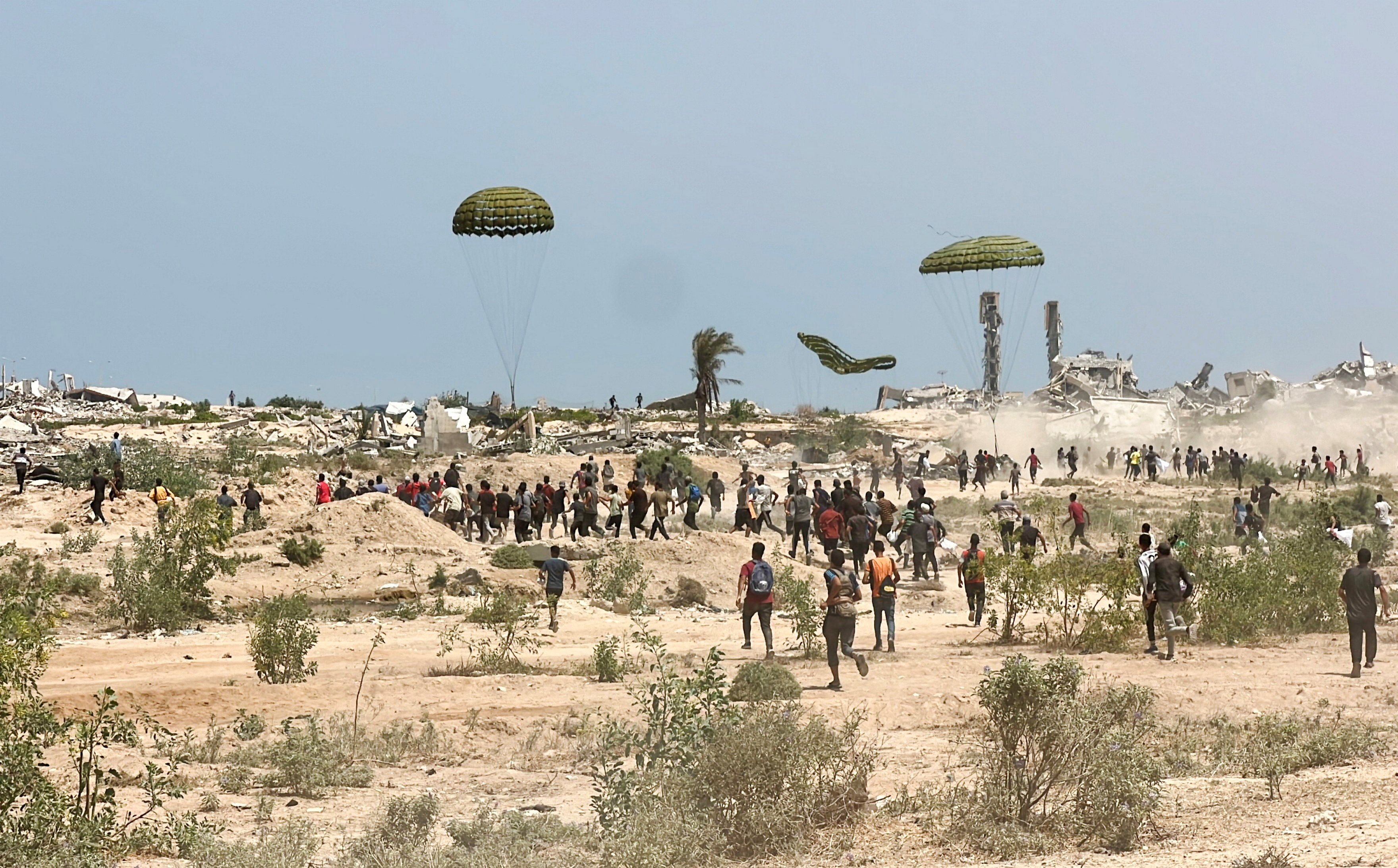 People scramble to collect parachuted aid supplies, at the site where a Palestinian boy died after he was struck by a box of airdropped aid, in the central Gaza Strip on Saturday. Photo: Reuters
