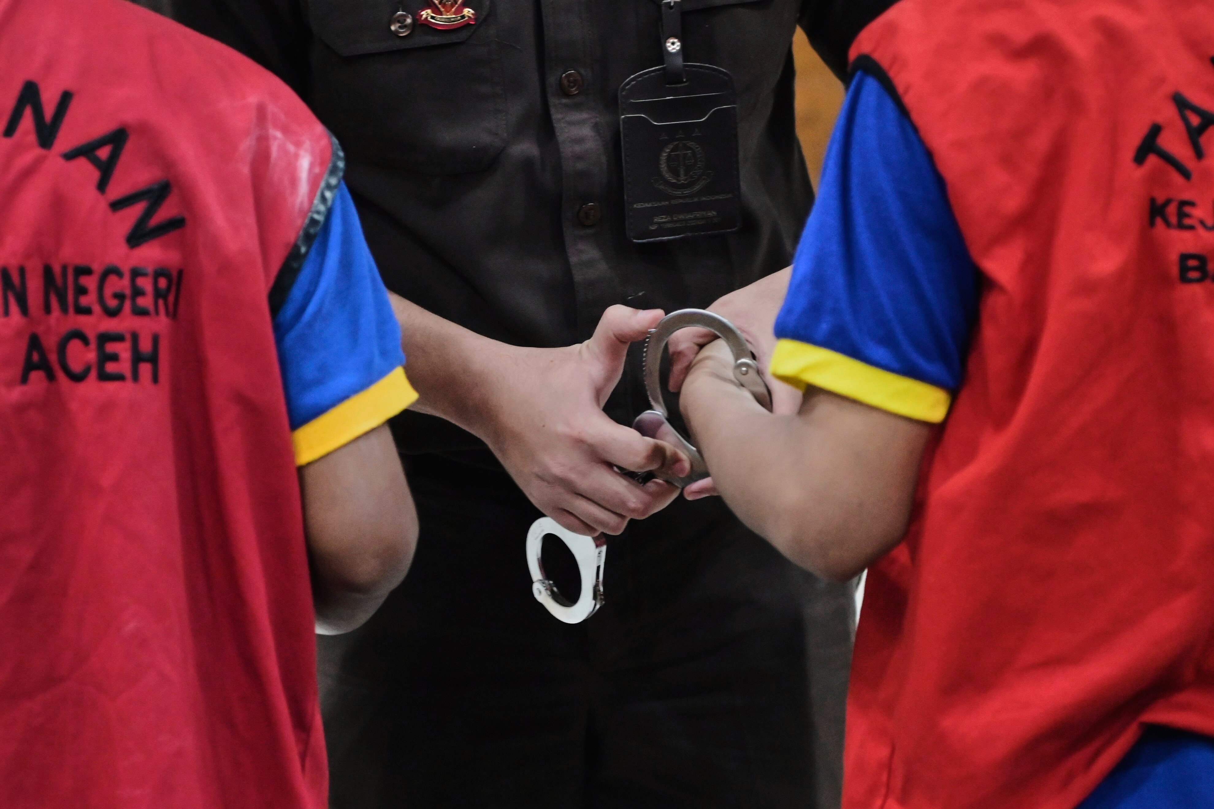 A prosecutor puts a handcuff on two men accused of having gay sex, after their sentencing hearing at a Sharia Court in Banda Aceh, Indonesia on Monday. Photo: AP