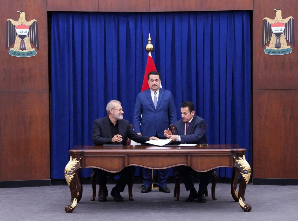 Iraqi Prime Minister Mohammed Shia al-Sudani looks on as Iraq’s National Security Adviser Qasim al-Araji and Ali Larijani, secretary of Iran’s Supreme National Security Council, sign documents in Baghdad, Iraq on Monday. Photo: Iraqi Prime Minister’s Media Office / Handout via Reuters