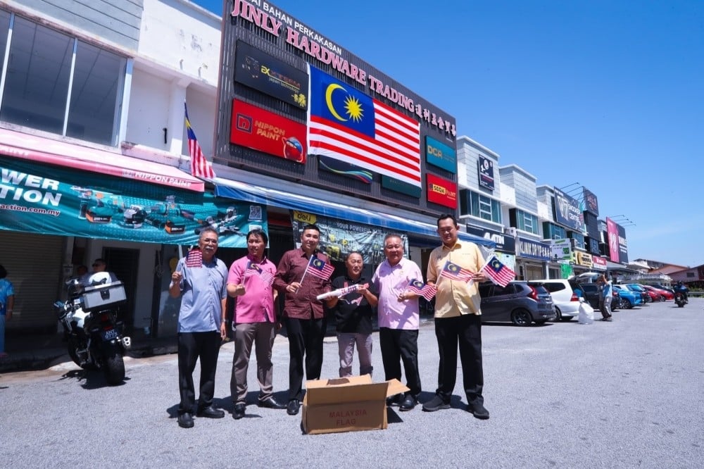 DAP members install a giant Malaysian flag on Wednesday outside a hardware store in Penang that recently went viral for flying the flag upside down. Photo: X/GenZMalaysia