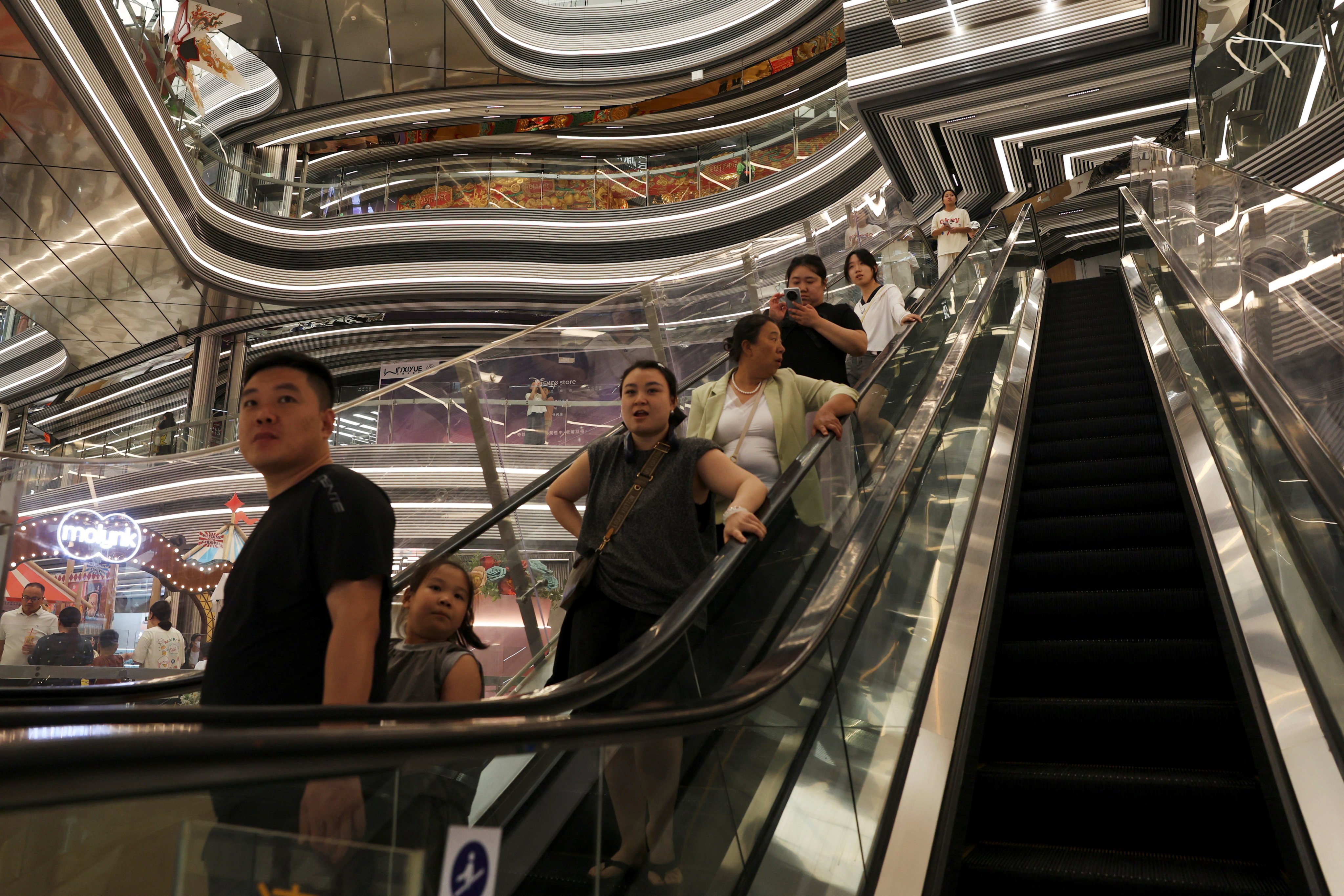People ride an escalator at a shopping centre in Beijing on July 31. Photo: Reuters