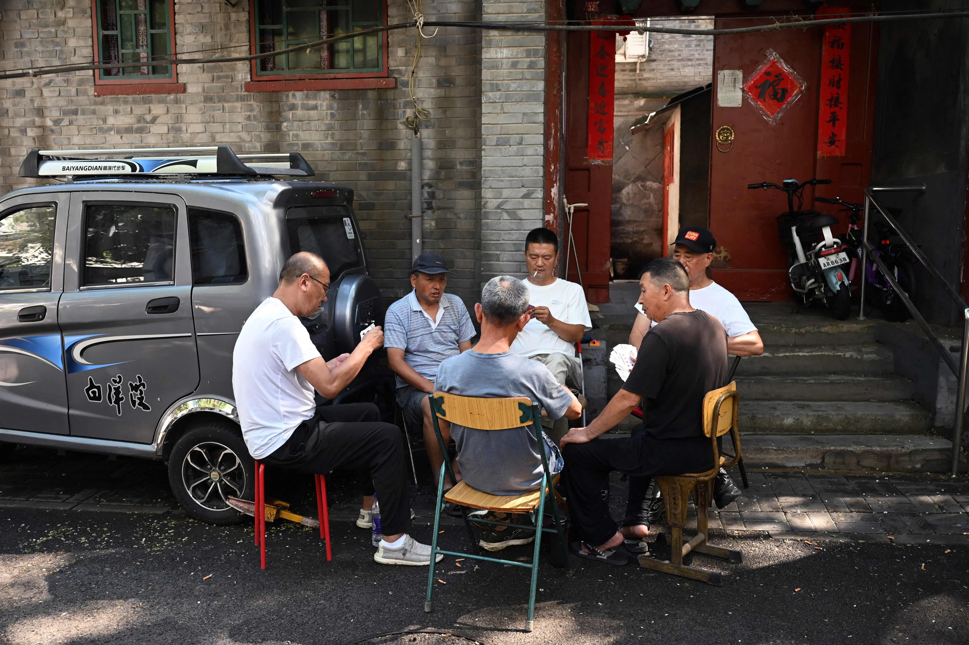 A group of men play cards in an alley in Beijing on July 29. When people live in a hutong, a narrow alleyway lined with siheyuan – courtyard-style residences – a culture of connection is baked in. Photo: AFP