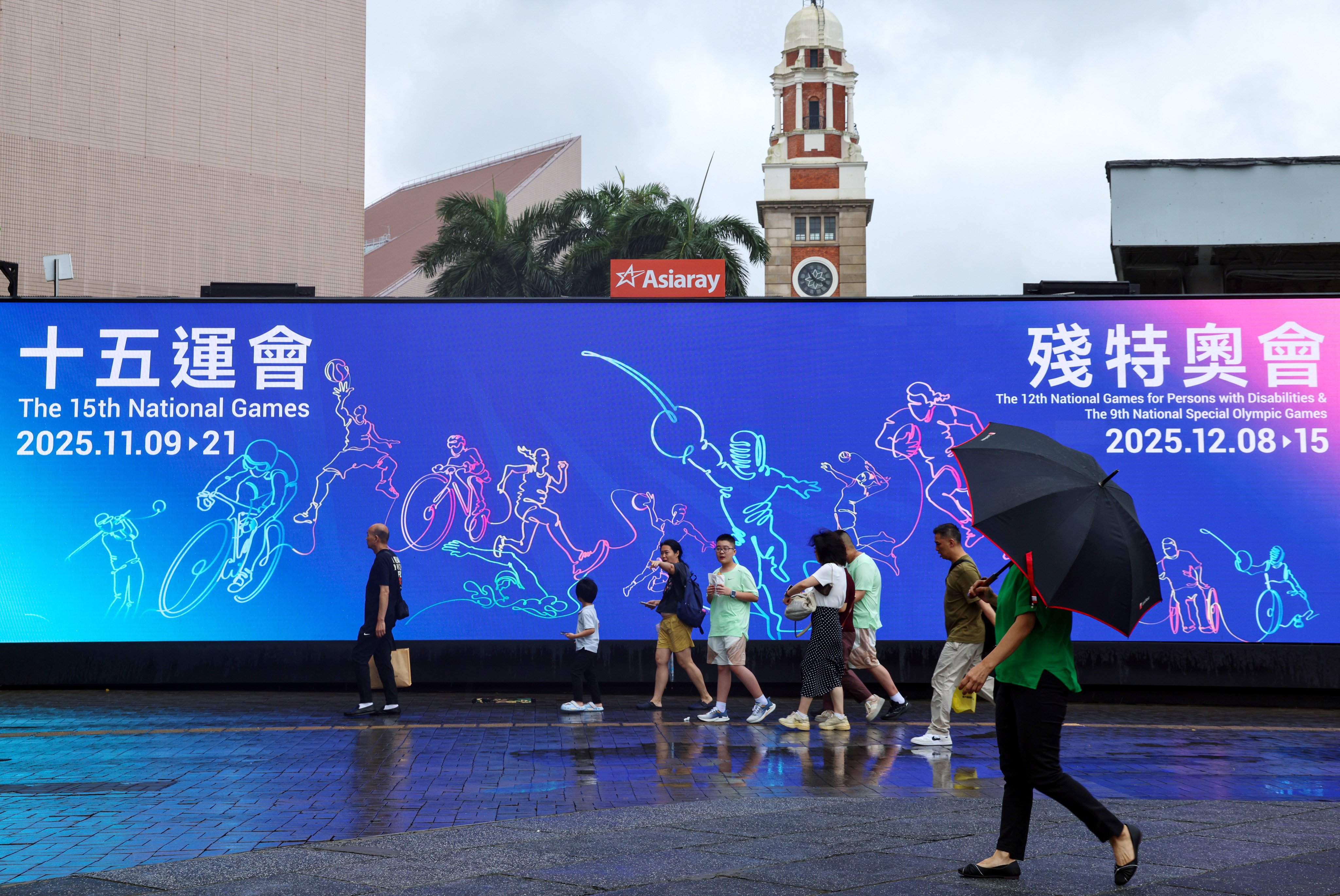 Residents walk past a large advertisement near the Tsim Sha Tsui Ferry Pier promoting the 15th National Games. Photo: Jelly Tse