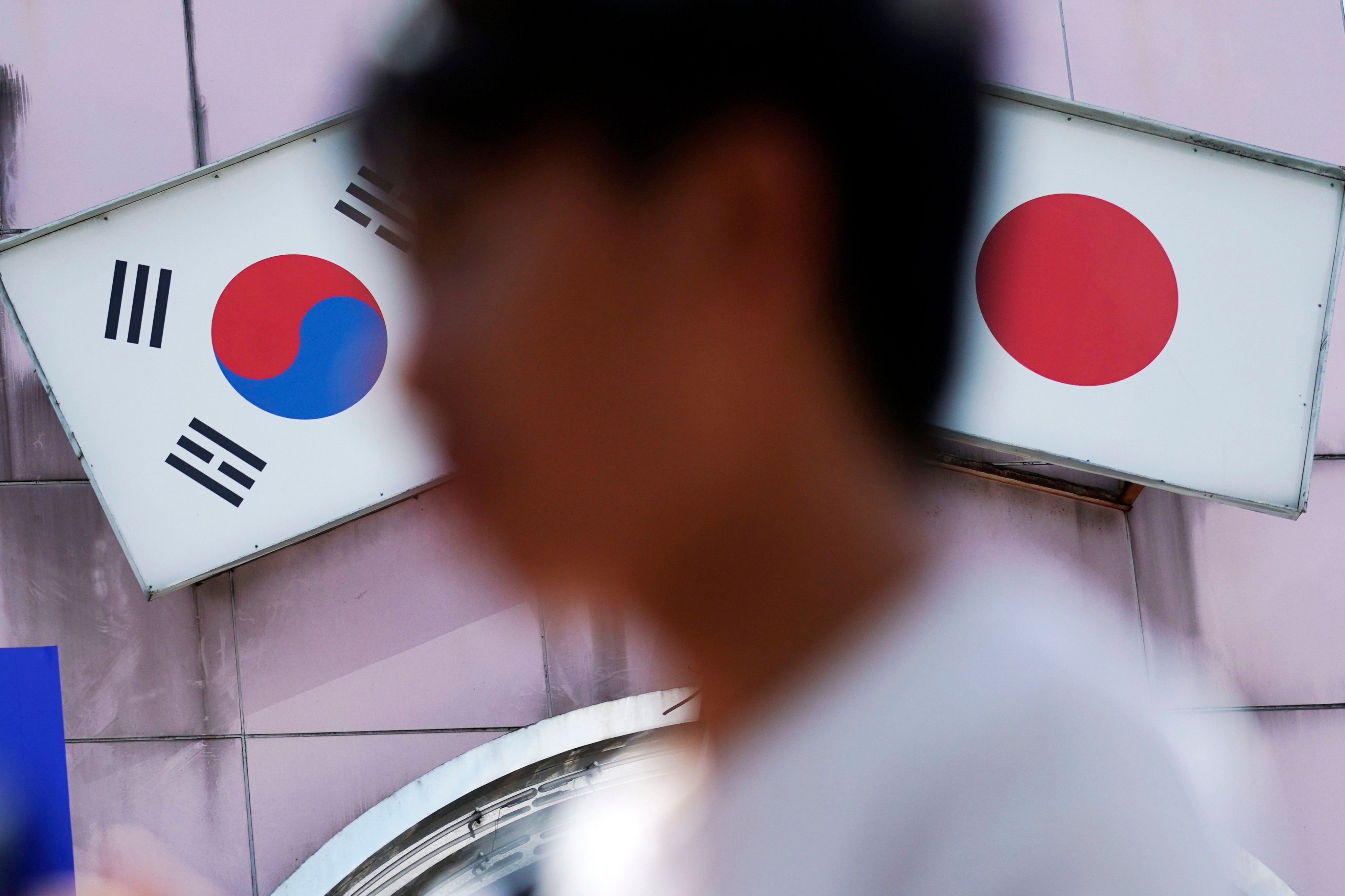 A man walks past an advertisement featuring Japanese and South Korean flags outside a shop in Tokyo. Photo: AP