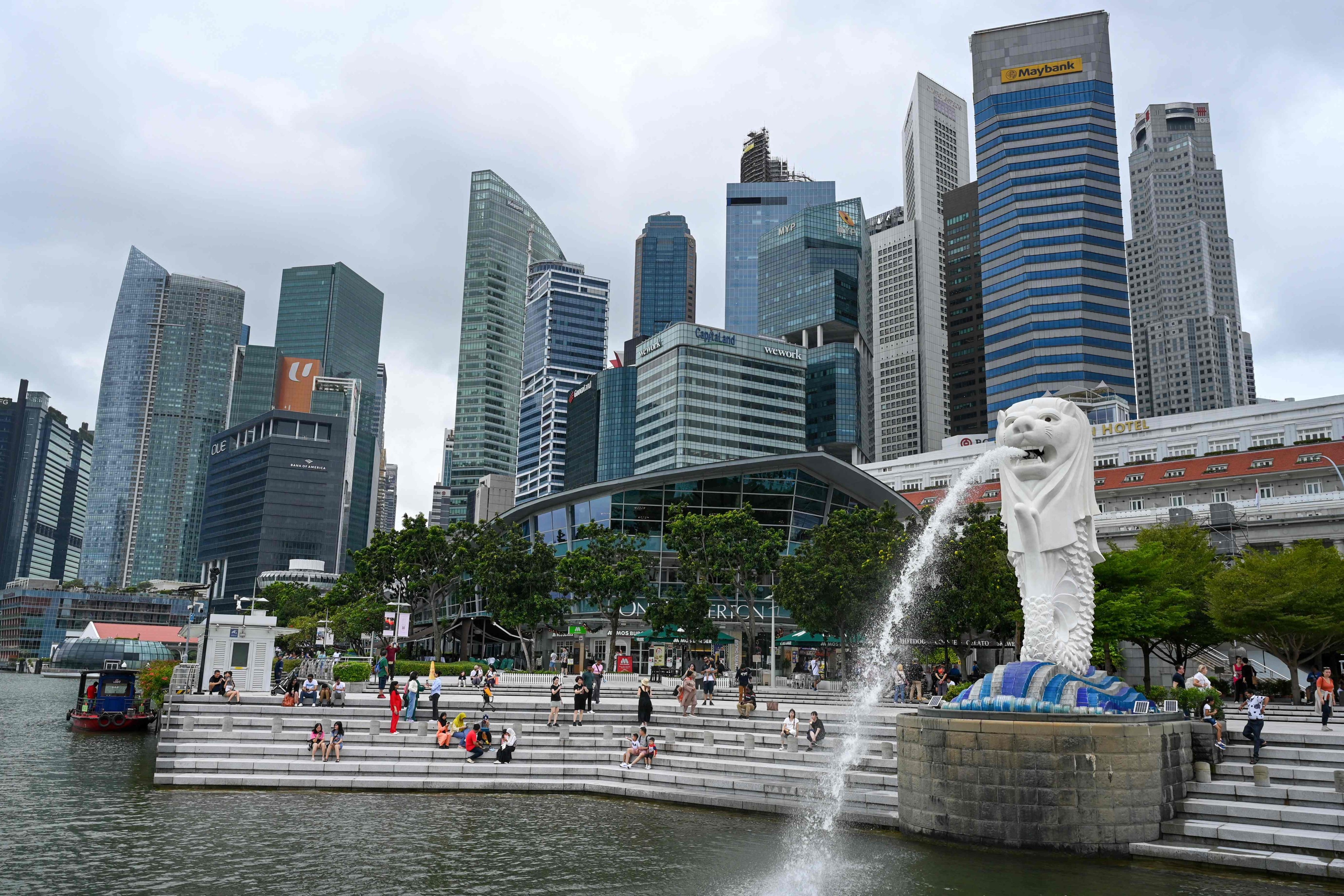 People sit on the steps near the Merlion statue near the Marina Bay waterfront in Singapore. Photo: AFP