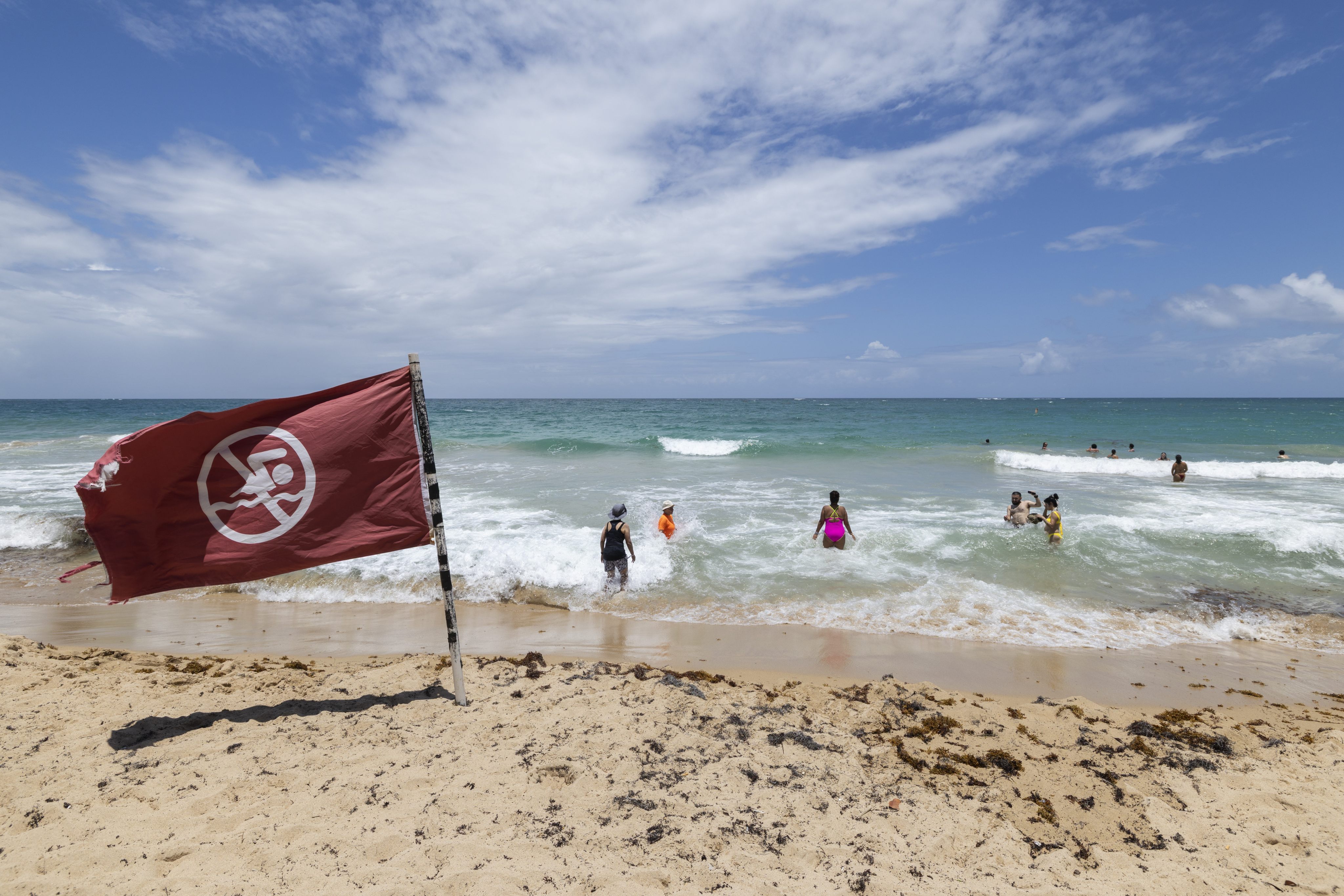 People disregard a warning flag on the beach in Condado, Puerto Rico, on Friday as Hurricane Erin approaches. Photo: AP