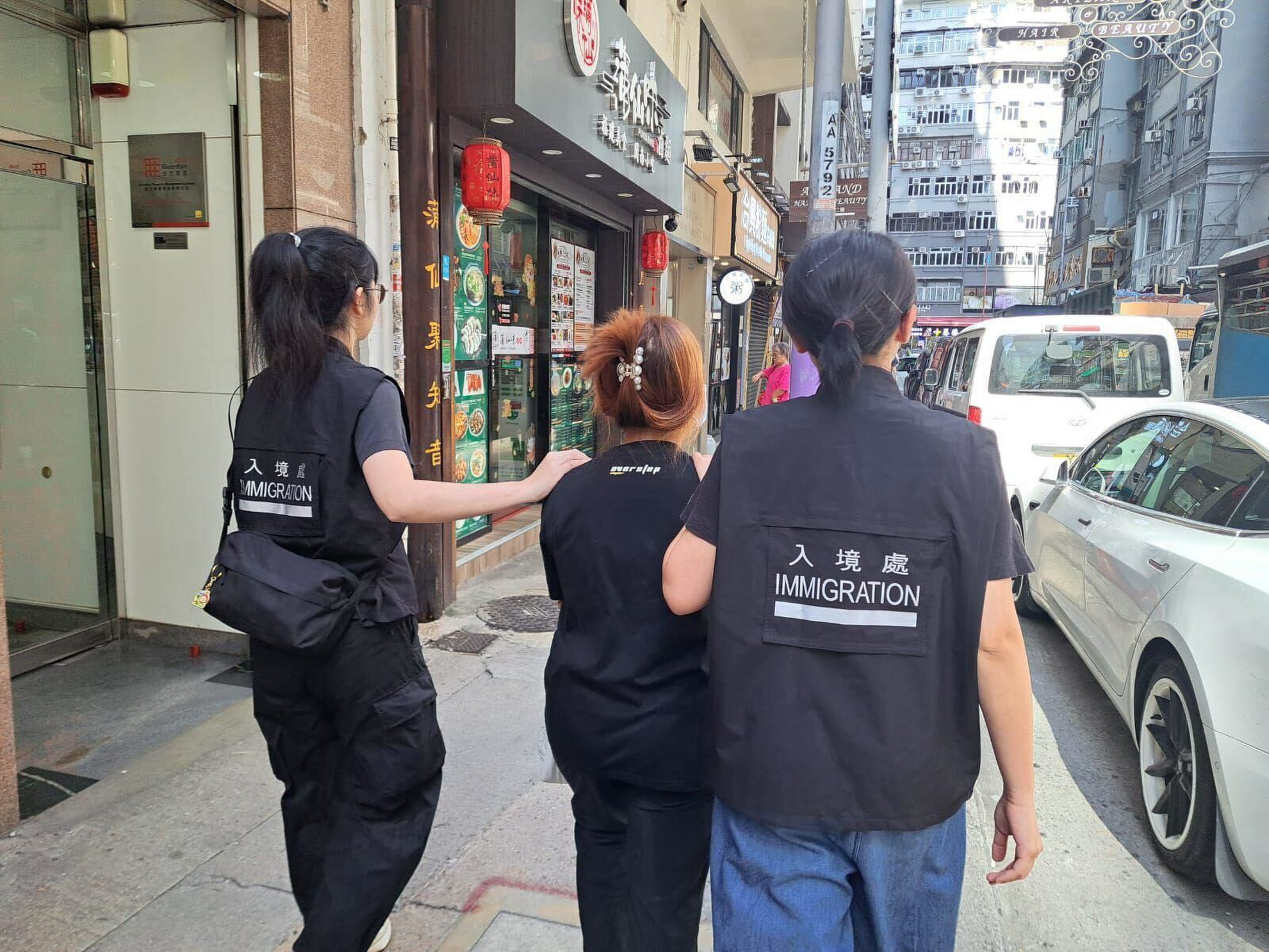 Immigration Department staff take away a suspect. Photo: Handout
