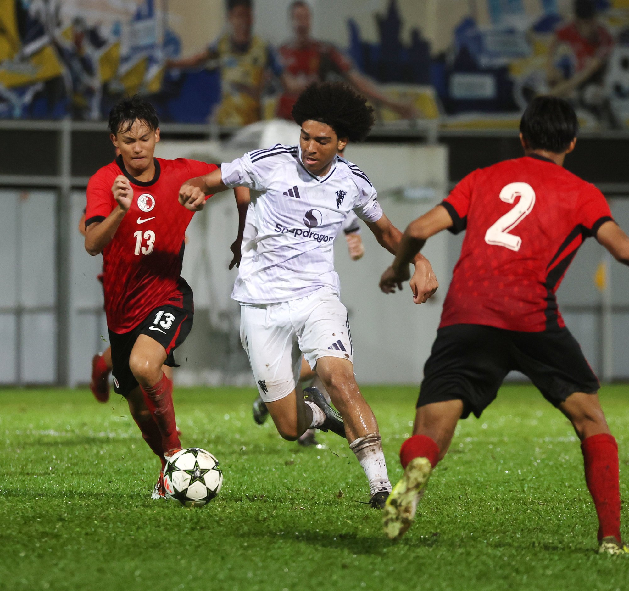 United's Camron (centre), who scored a hat-trick, runs between two Hong Kong defenders. Photo: Edmond So