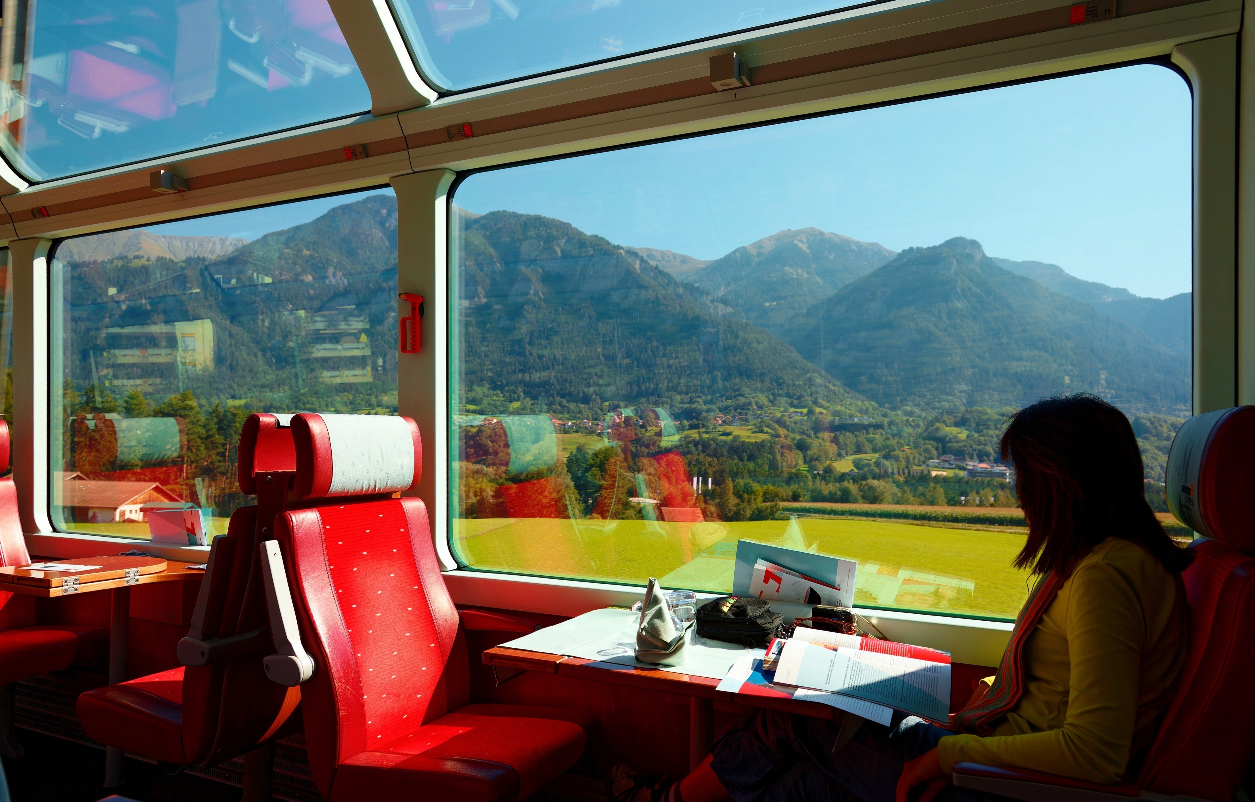 A passenger on the Glacier Express train enjoys a view of the Swiss countryside. A train journey tends to be more comfortable and better for the environment than a flight, although it is slower and can even sometimes be more expensive. Photo: Shutterstock