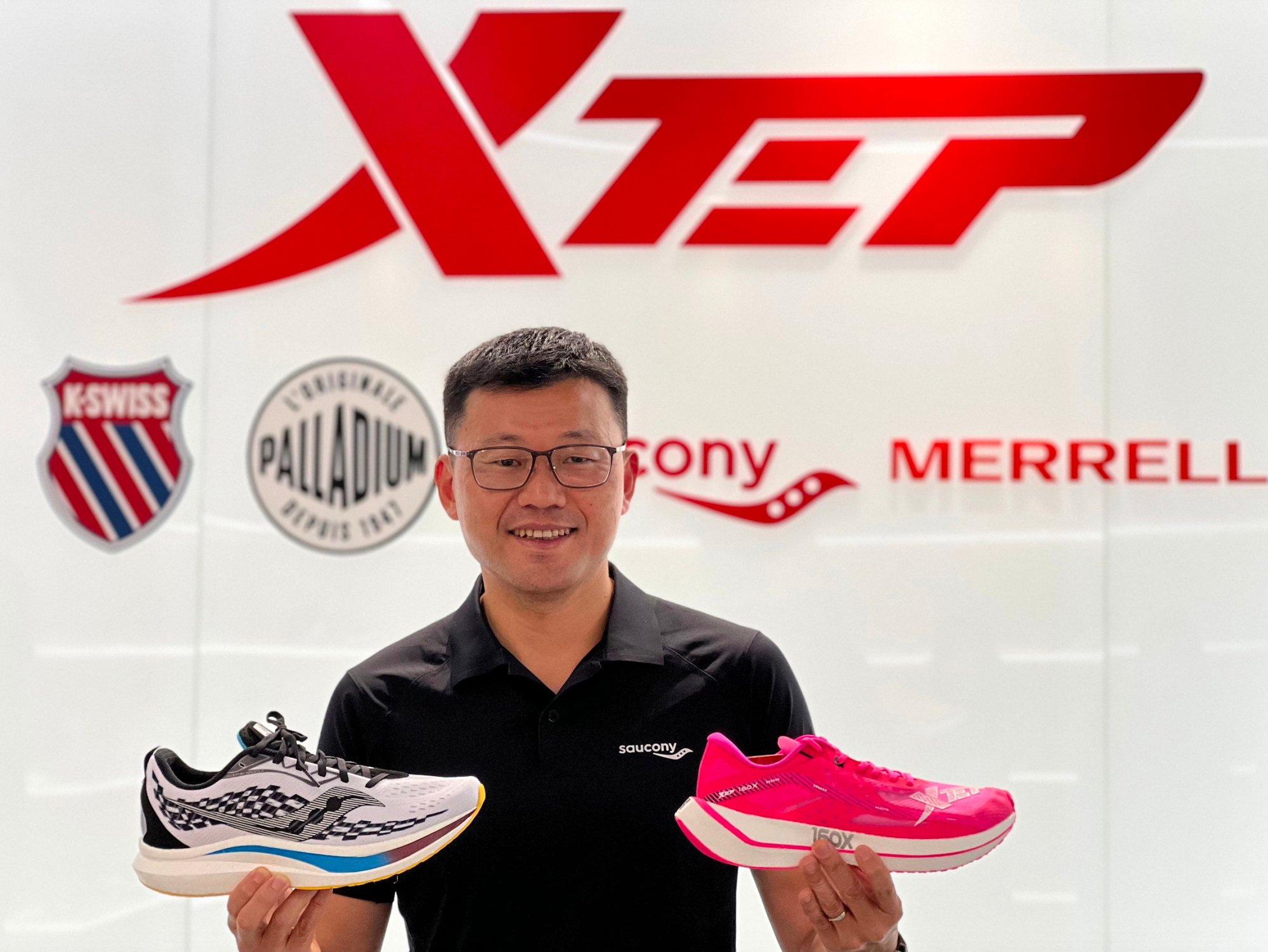 Xtep International's chief financial officer Ricky Yeung, holding a Saucony (left) running shoe and an Xtep shoe (right), on April 10, 2022. Photo: Handout