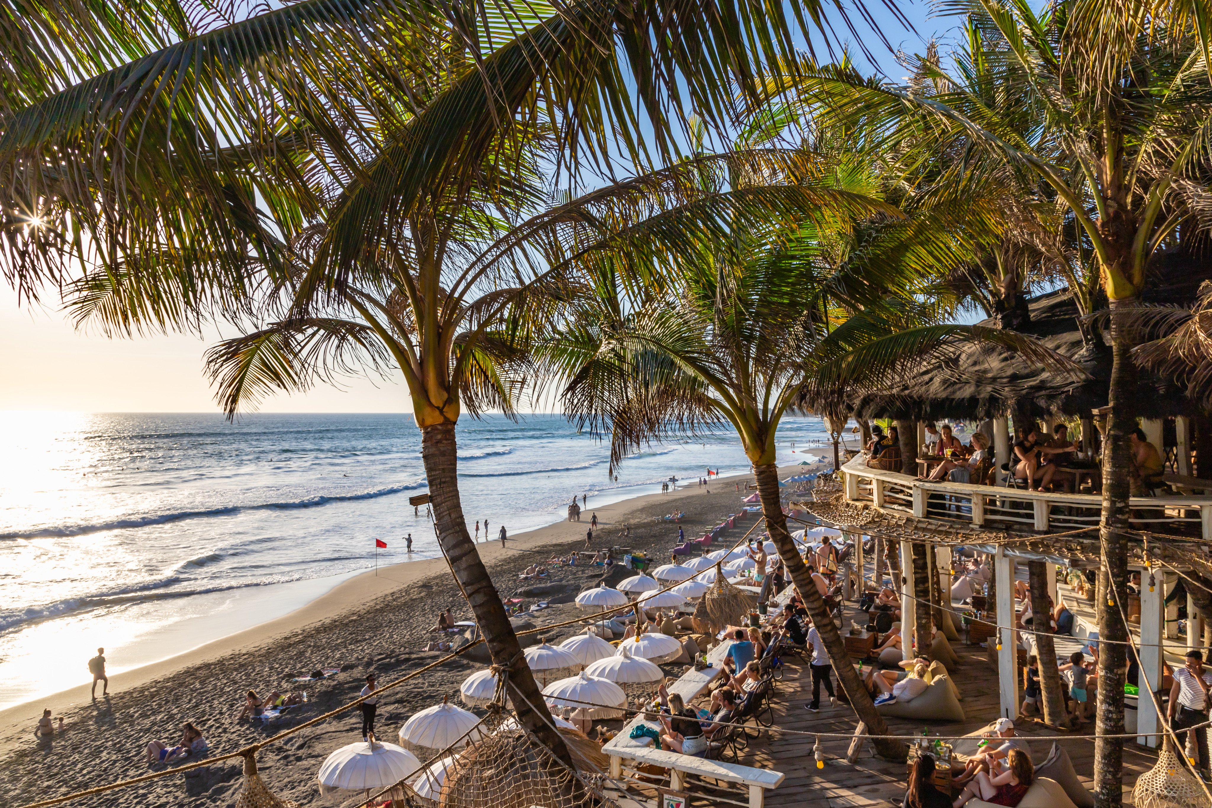 View of a beach restaurant terrace, crowded with tourists at the famous Echo Beach at sunset. Photo: Shutterstock