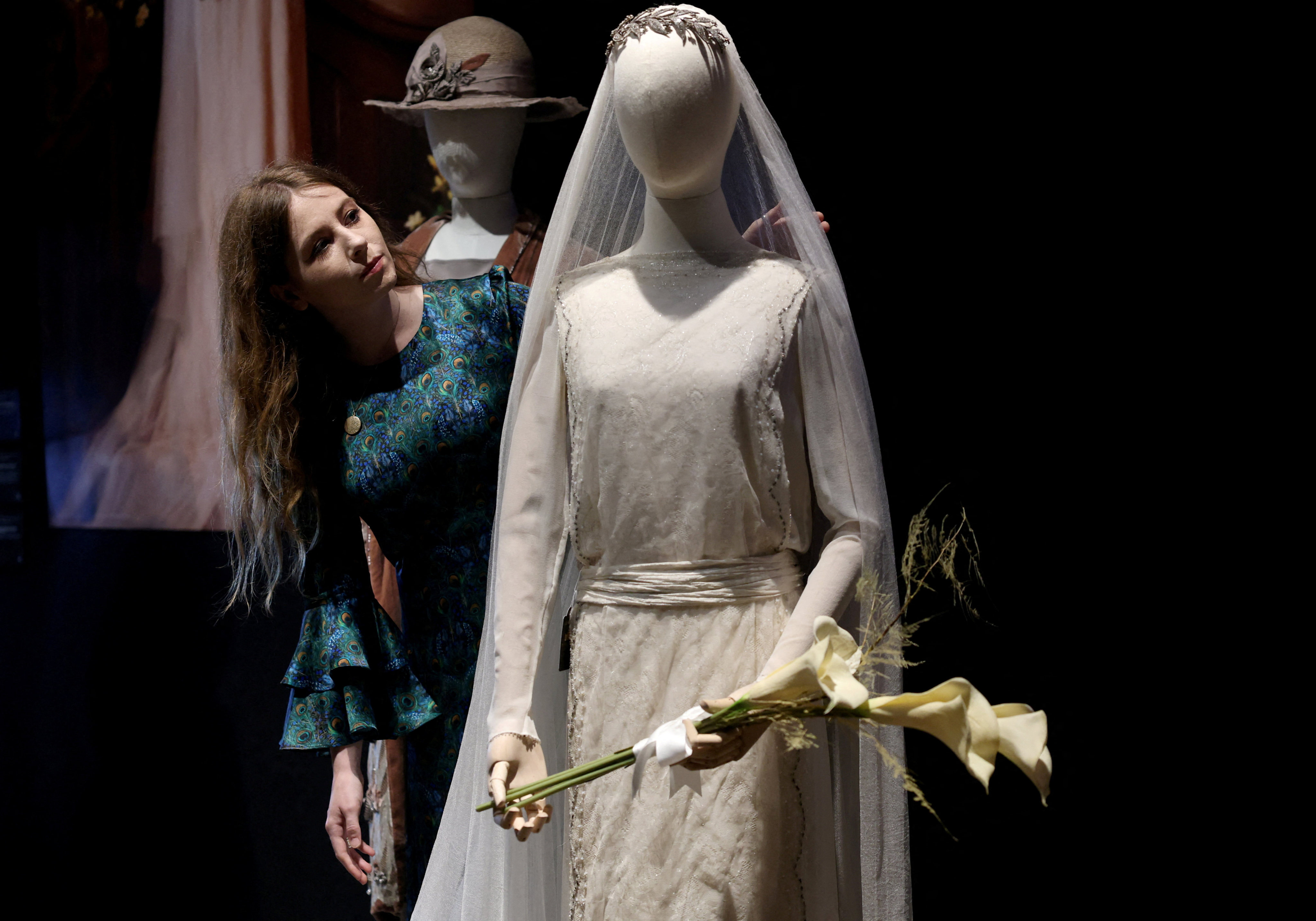 A gallery assistant poses with a wedding prop costume and a bouquet worn by actress Michelle Dockery (as Lady Mary) in Downton Abbey, season 3, episode 1, during a press preview for the Downton Abbey farewell exhibition and an auction of props, costumes, and set pieces at Bonhams in London, Britain, August 18, 2025. REUTERS/Hannah McKay         TPX IMAGES OF THE DAY