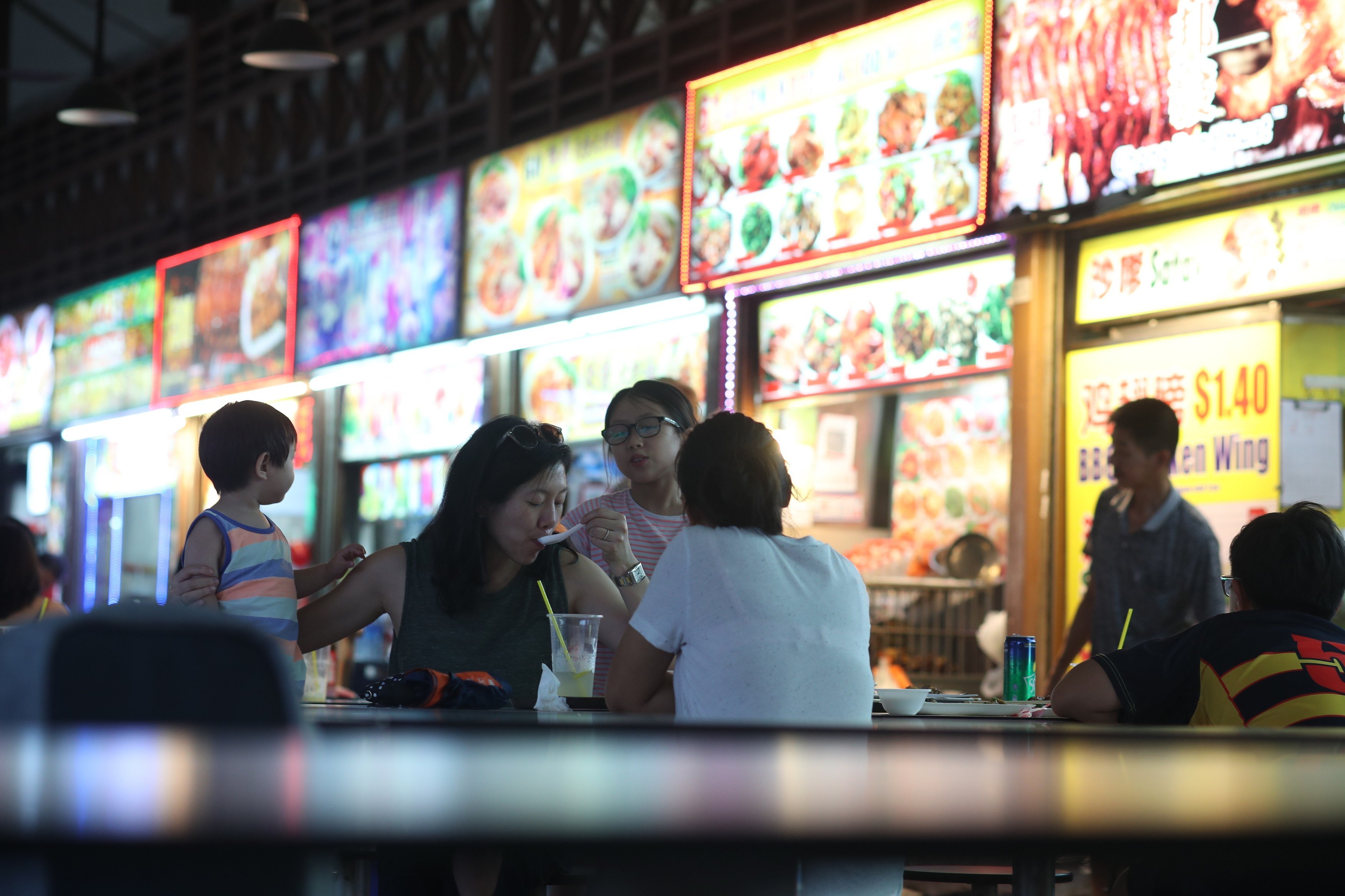 Customers eat local foods purchased from hawker stalls at the Newton Food Centre in Singapore. Photo: EPA-EFE