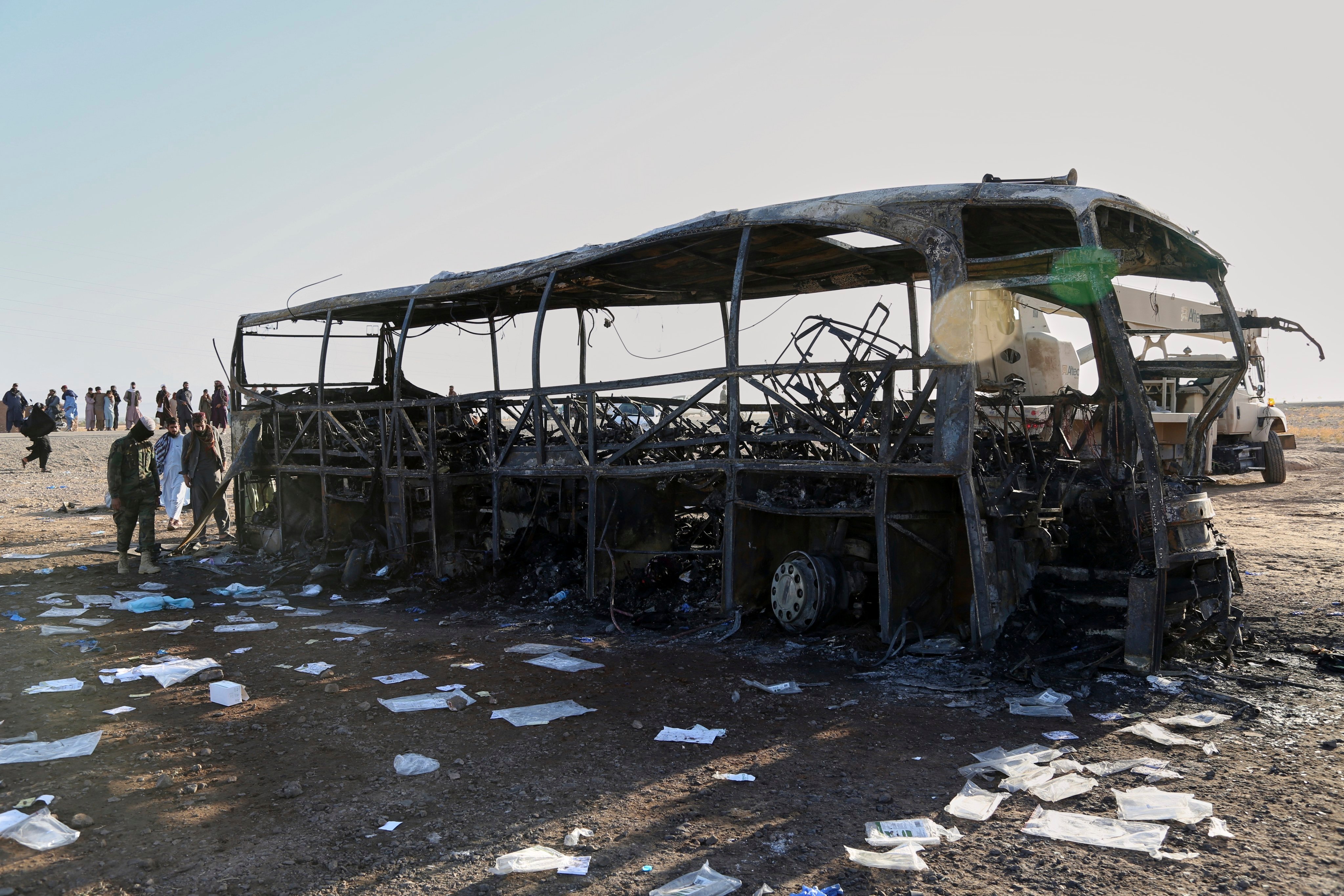 People and soldiers from the Taliban army inspect a burned-out bus that collided with a truck and a motorbike on Tuesday evening. Photo: AP