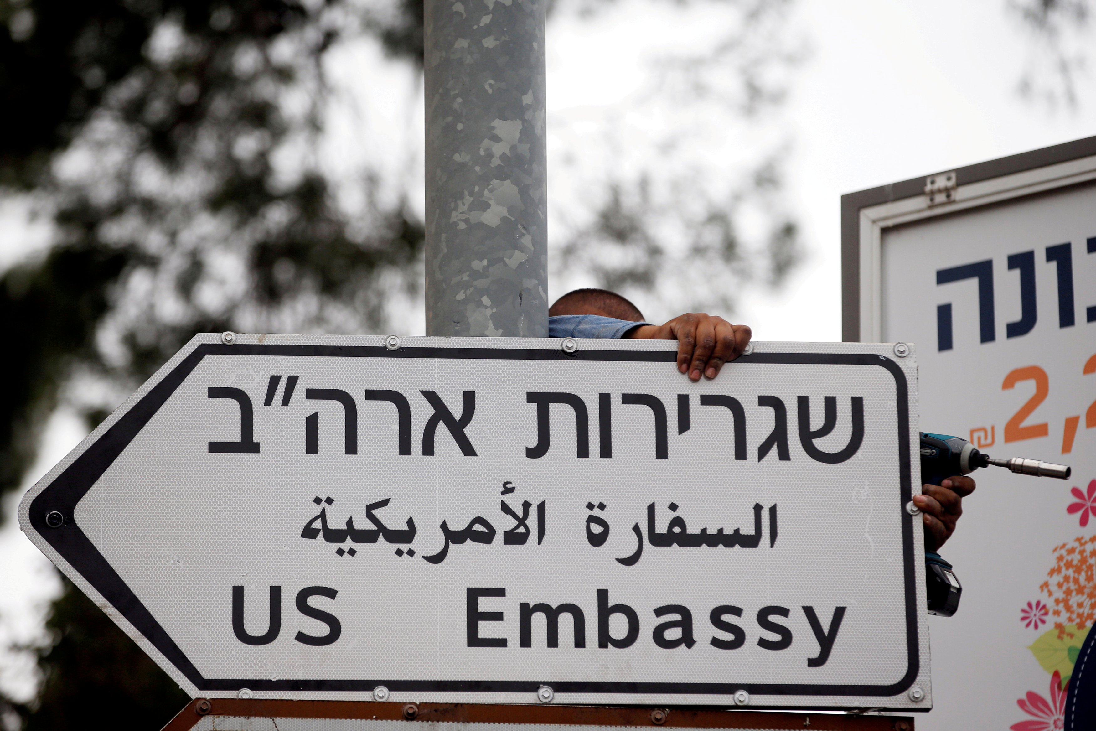 A worker hangs a road sign directing to the US Embassy in Jerusalem. Photo: Reuters