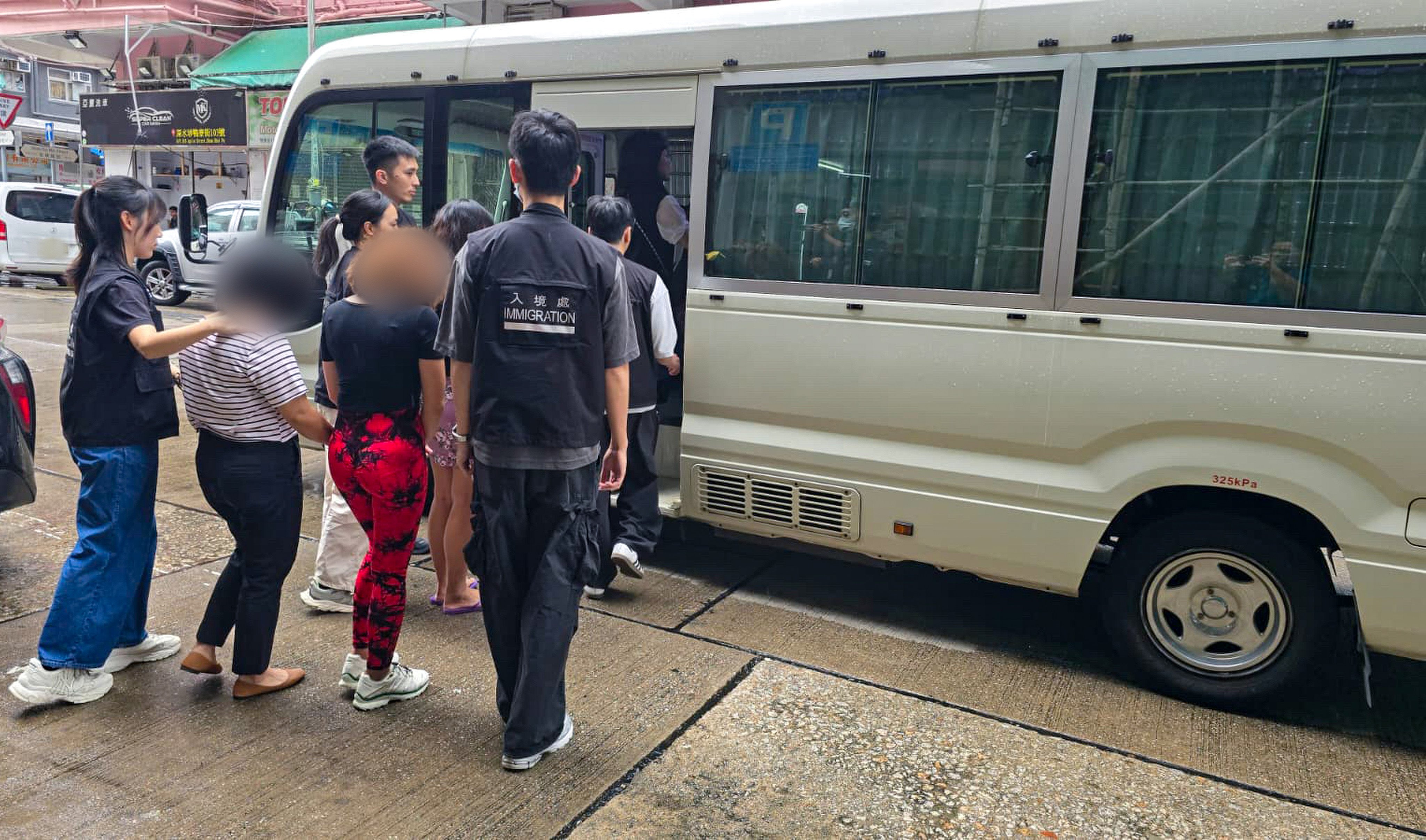 Filipino domestic workers caught operating an illegal dental clinic in a Hong Kong tenement building are loaded into a van last Sunday. Photo: Handout