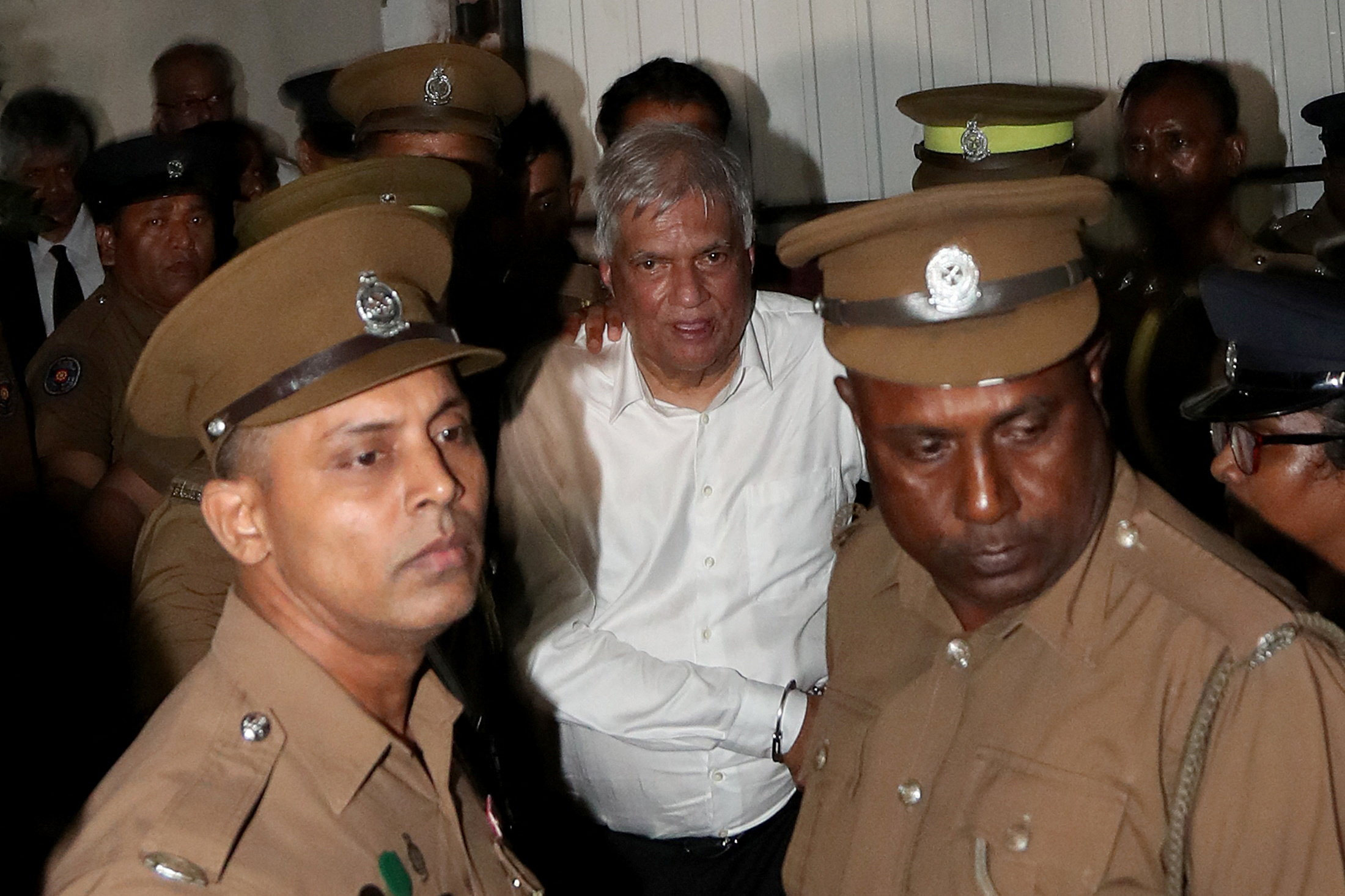 Sri Lanka’s former President Ranil Wickremesinghe is escorted by prison and police officials as he leaves the Magistrate’s Court in Colombo, Sri Lanka on Friday. Photo: Reuters