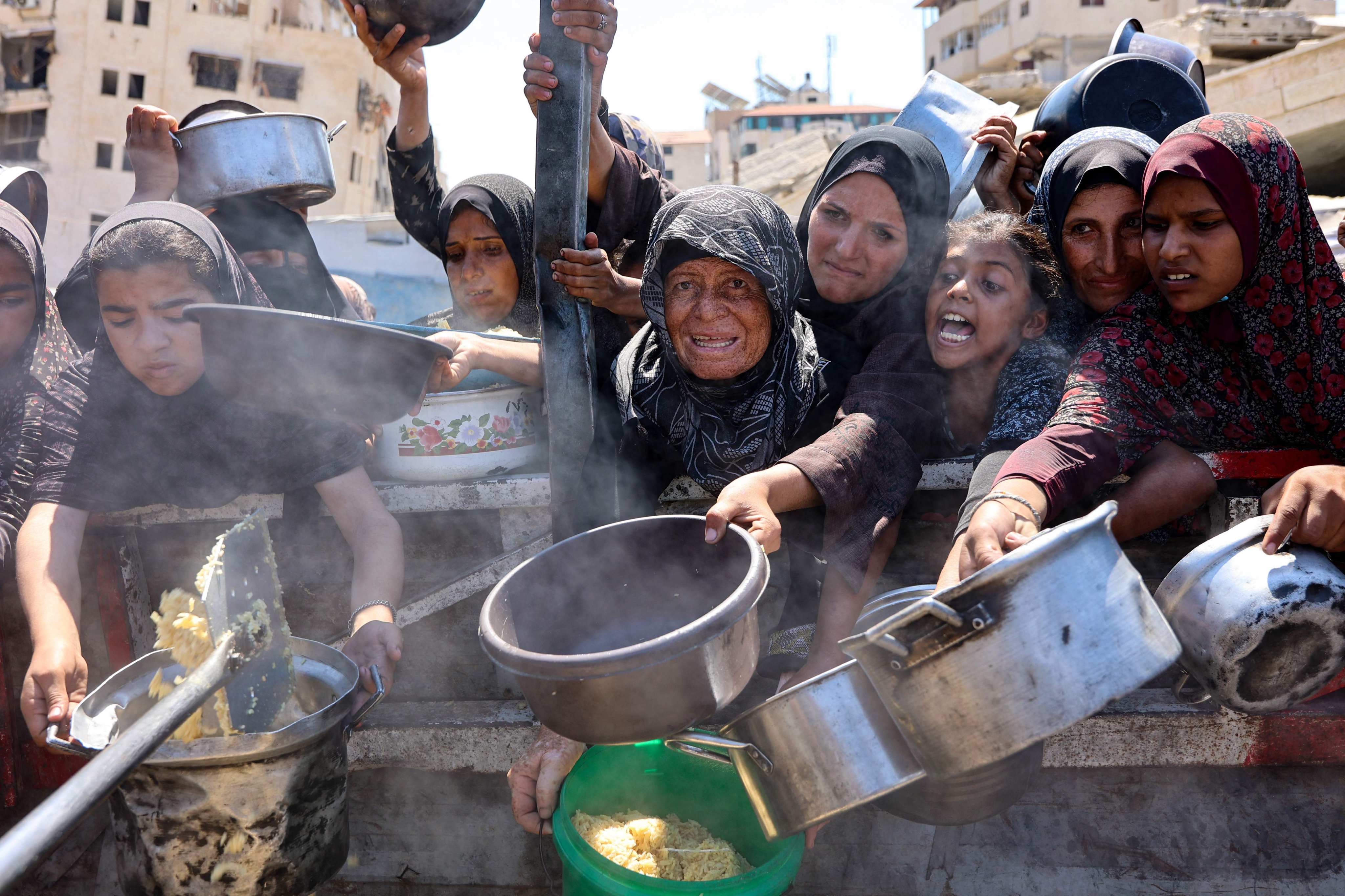 Palestinian women and girls elbow their way to receive cooked rice from a charity kitchen in Gaza City at the weekend. Photo: AFP