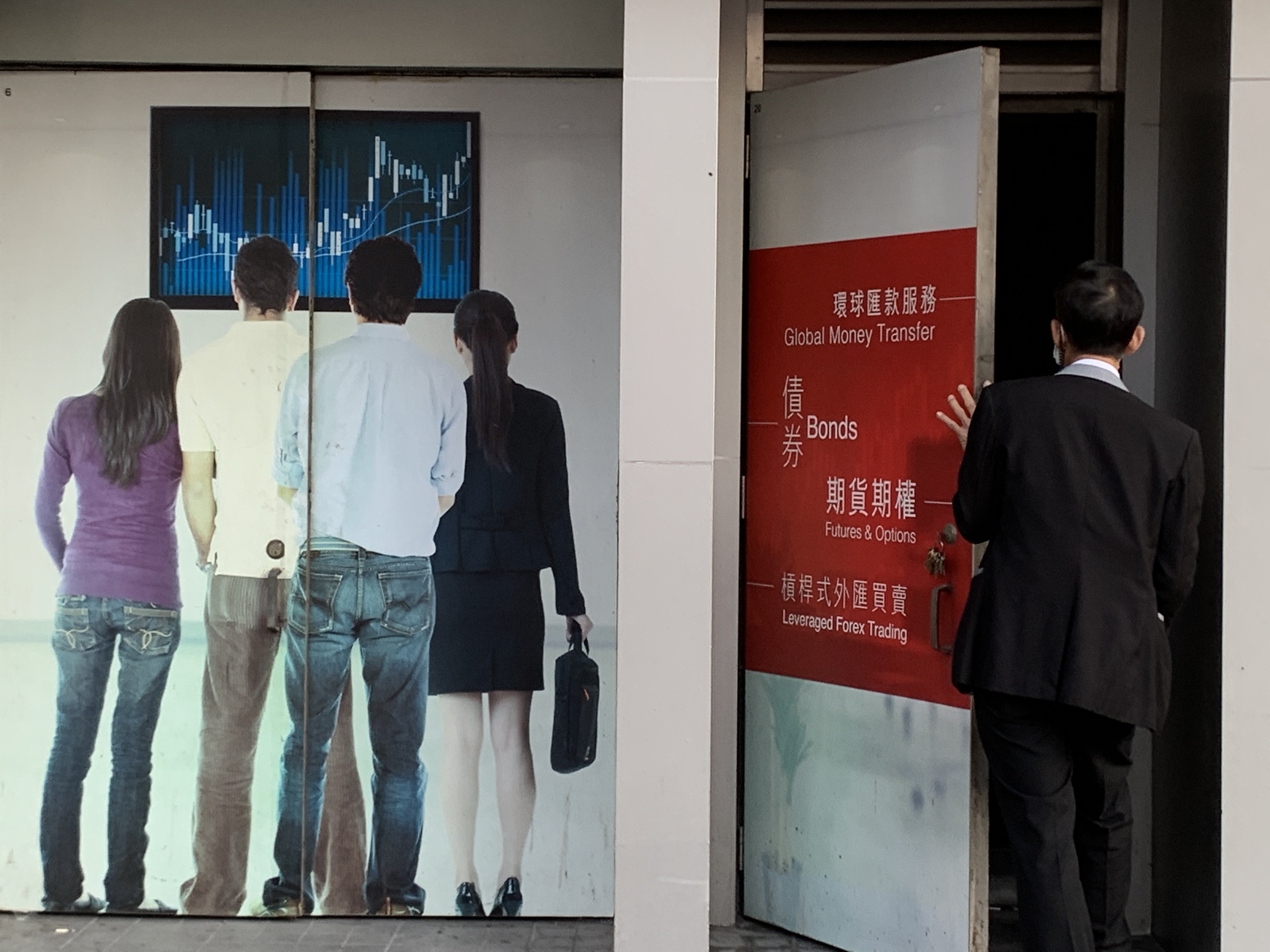 A security guard opens a door adjacent to an advertising billboard at a securities firm in Mong Kok on January 26, 2021. Photo: Nora Tam