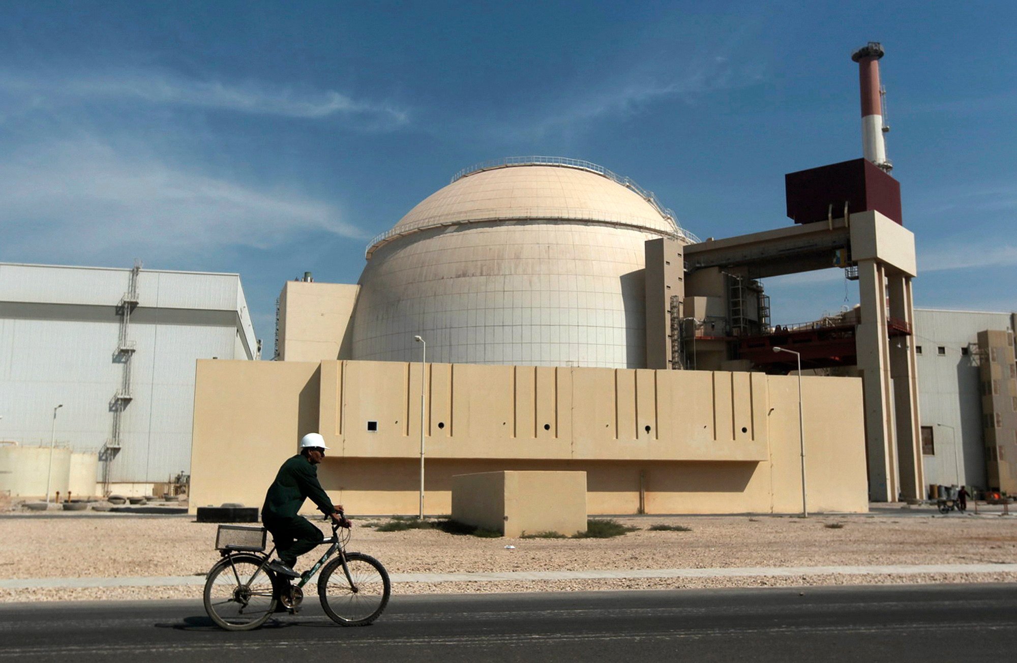 A worker rides a bicycle in front of the reactor building of the Bushehr nuclear power plant in Iran. Photo: AP