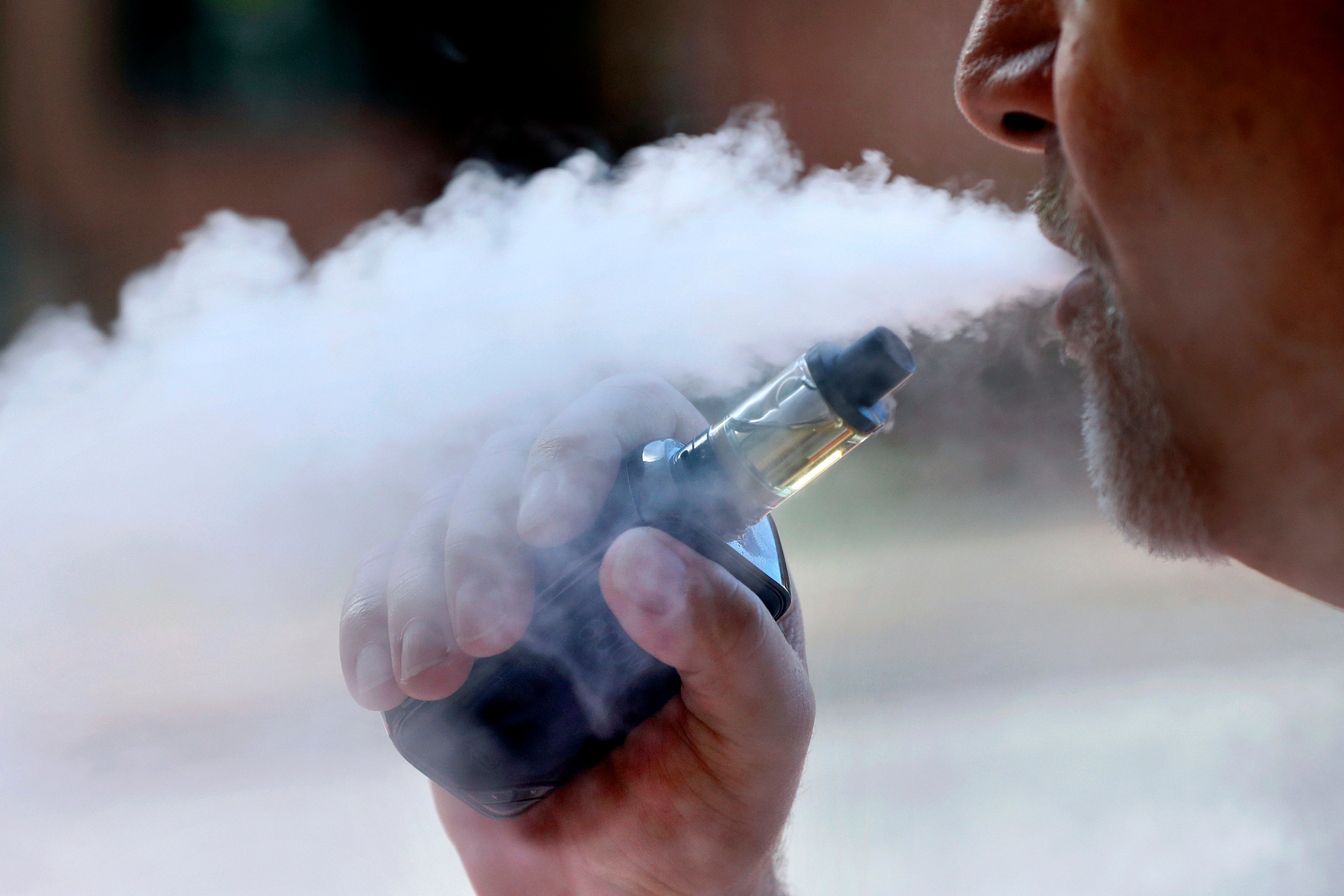 A man exhales while smoking an e-cigarette. Photo: AP