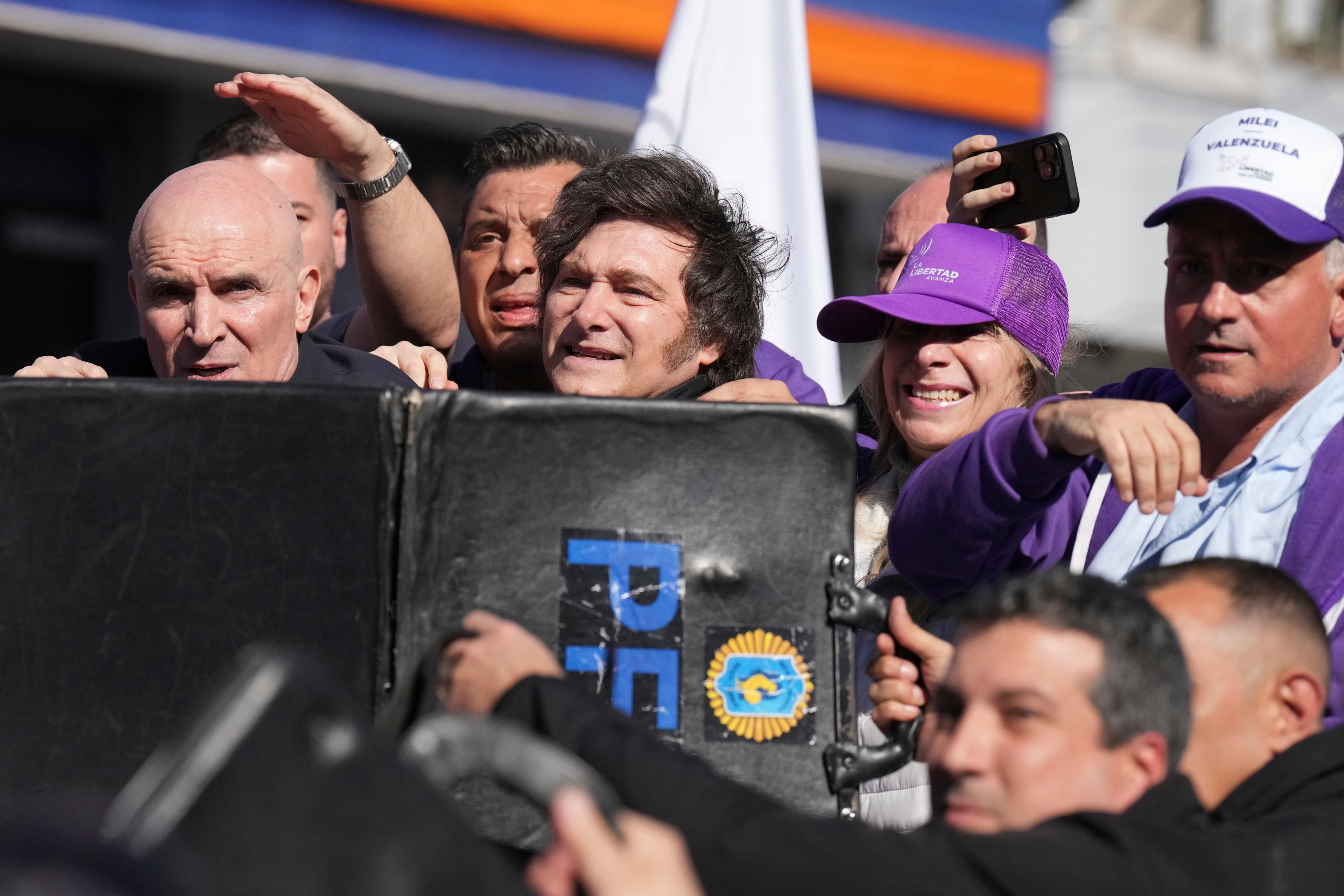 Police shield Argentine President Javier Milei and his sister, Secretary General of the Presidency Karina Milei, from objects thrown at them during a campaign rally in Lomas de Zamora on Wednesday. Photo: AP