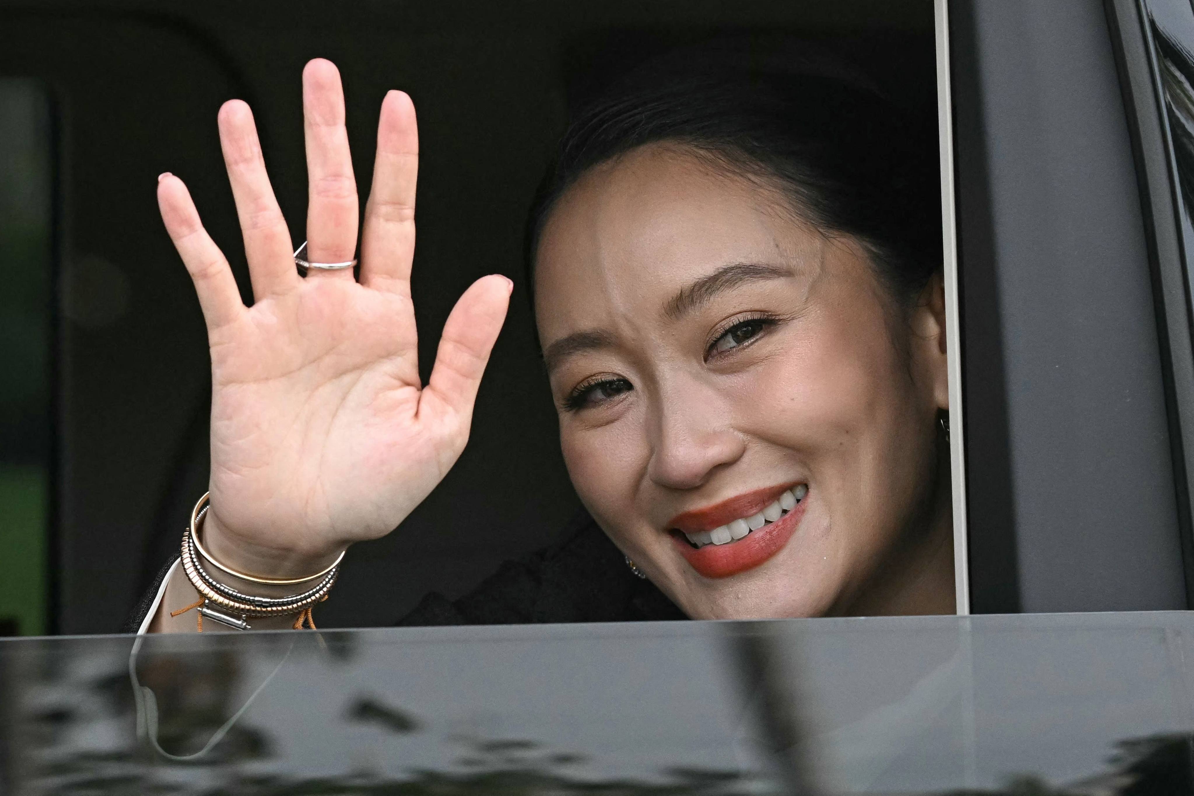 Thailand’s sacked prime minister Paetongtarn Shinawatra waves from a car as she leaves Government House after her dismissal by the Constitutional Court in Bangkok on Friday. Photo: AFP
