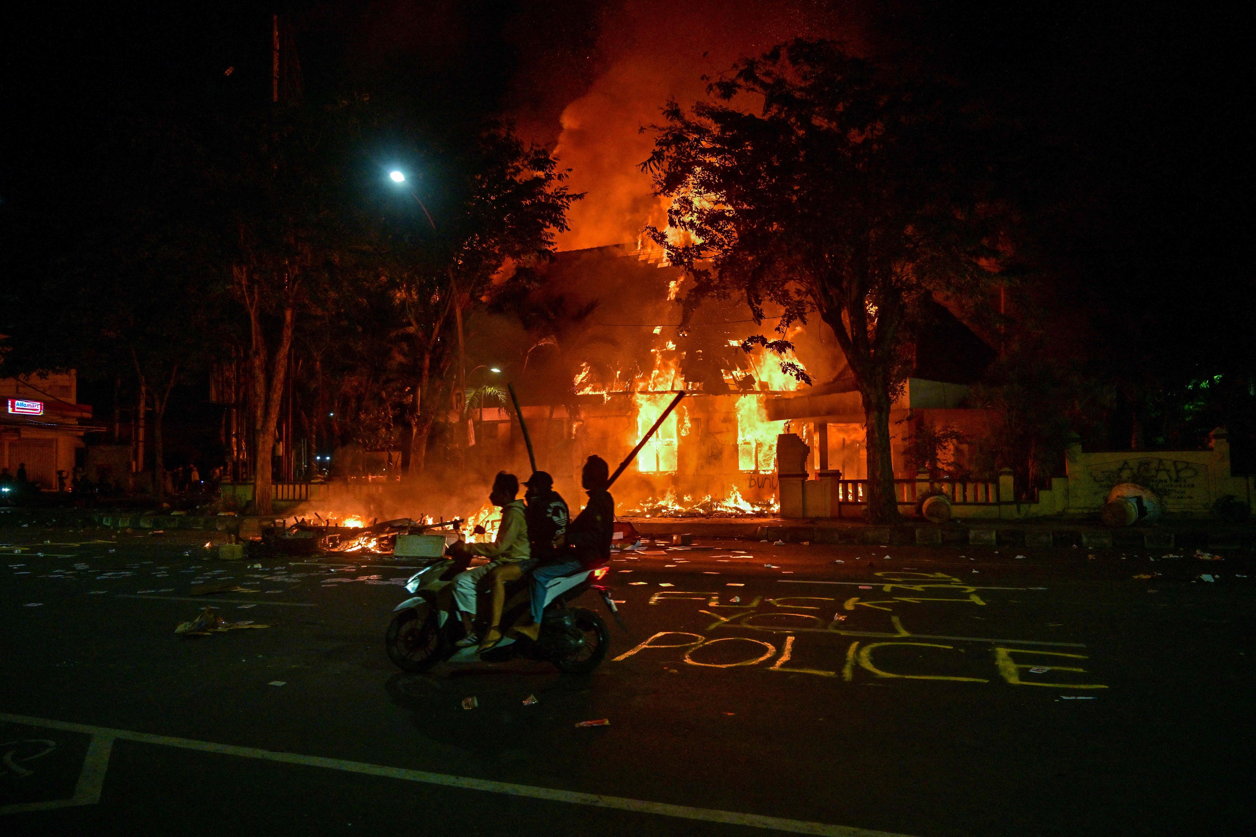 Indonesian protesters ride a motorcycle in front of a police headquarters that was burned and looted during demonstrations in Surabaya on Sunday. Photo: AFP