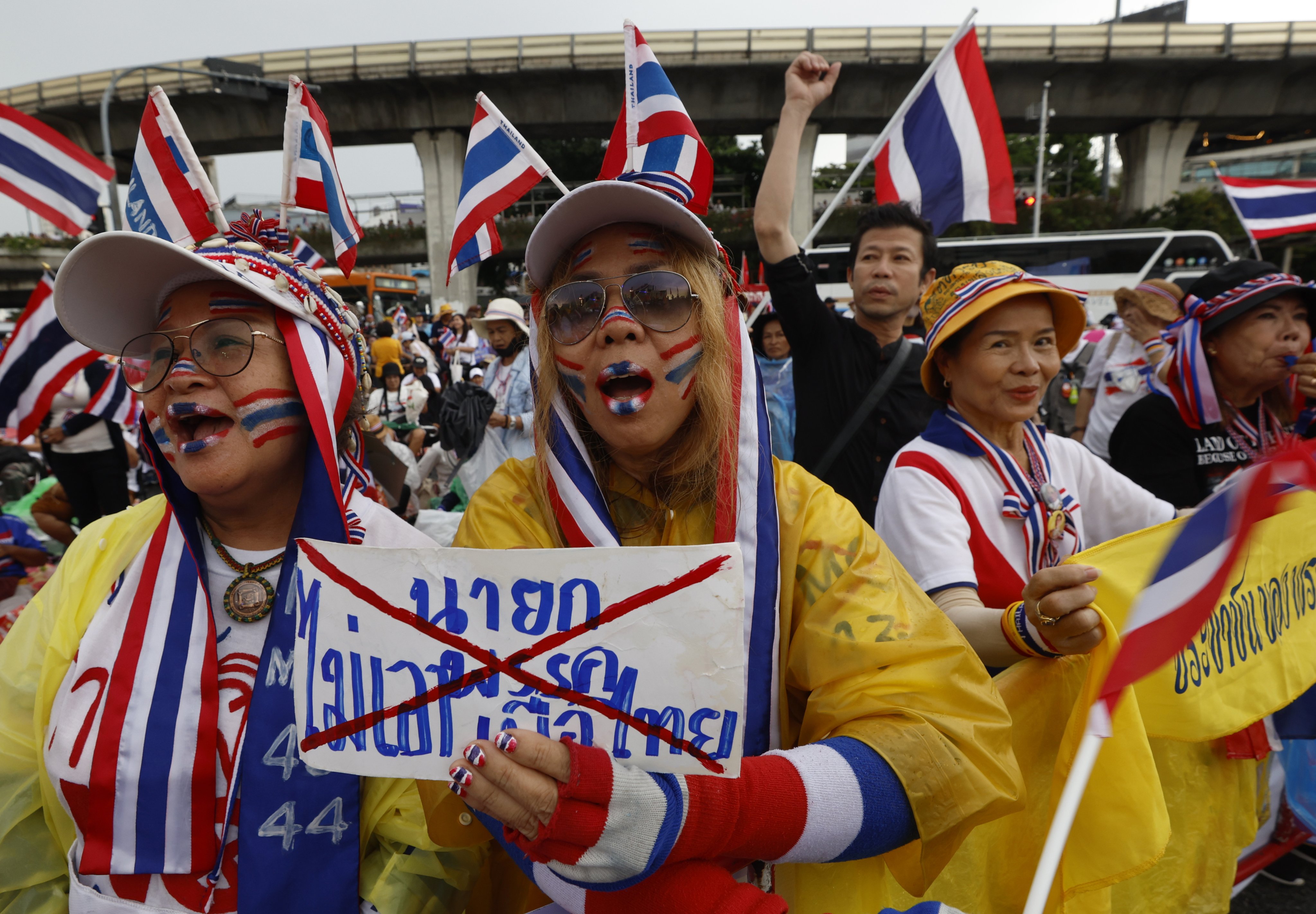 Demonstrators wearing accessories and face paint in the colours of Thailand’s national flag hold a sign reading ‘No prime minister from the Pheu Thai Party’ during a protest in Bangkok on Sunday. Photo: EPA