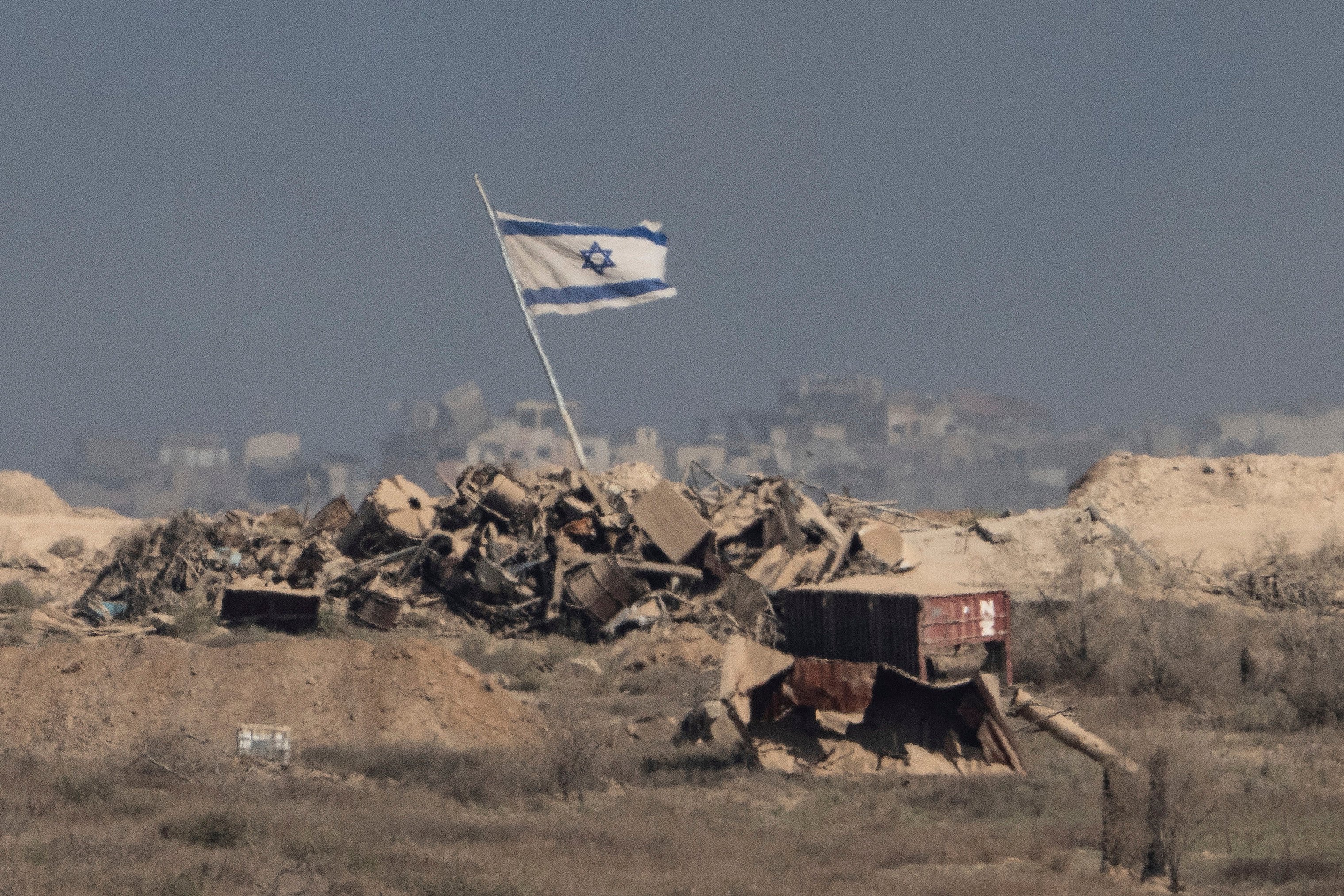 An Israeli flag waves over debris in an area of the Gaza Strip, as seen from southern Israel. Photo: AP