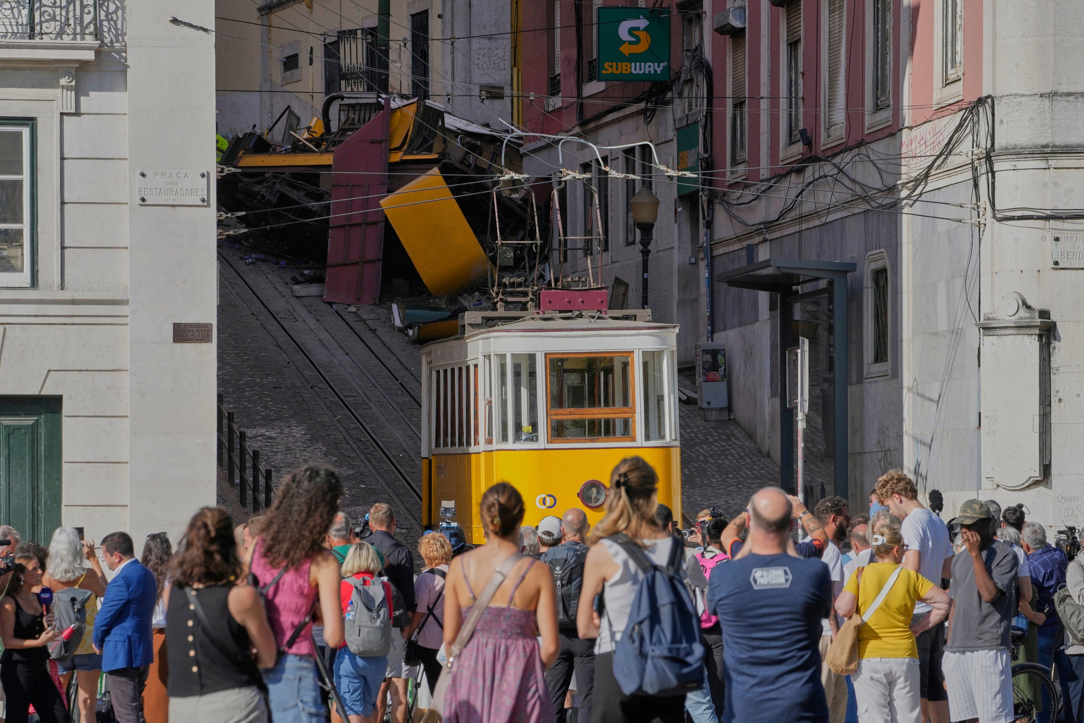 People pass the crashed tourist streetcar in Lisbon. Photo: AP