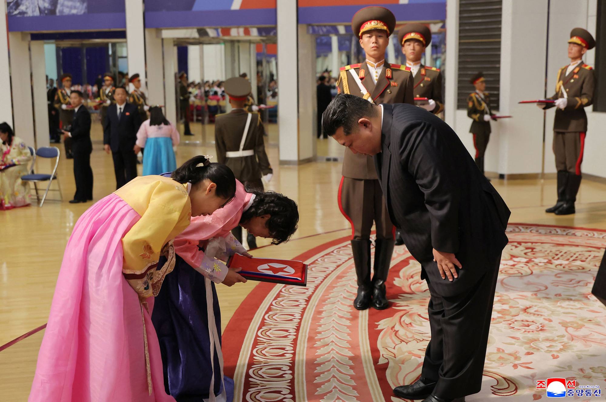 In Pyongyang on August 29, North Korean leader Kim Jong-un hands over a portrait wrapped in the North Korean flag to the family of a soldier who took part in overseas military operations. Photo: AFP / KCNA via KNS