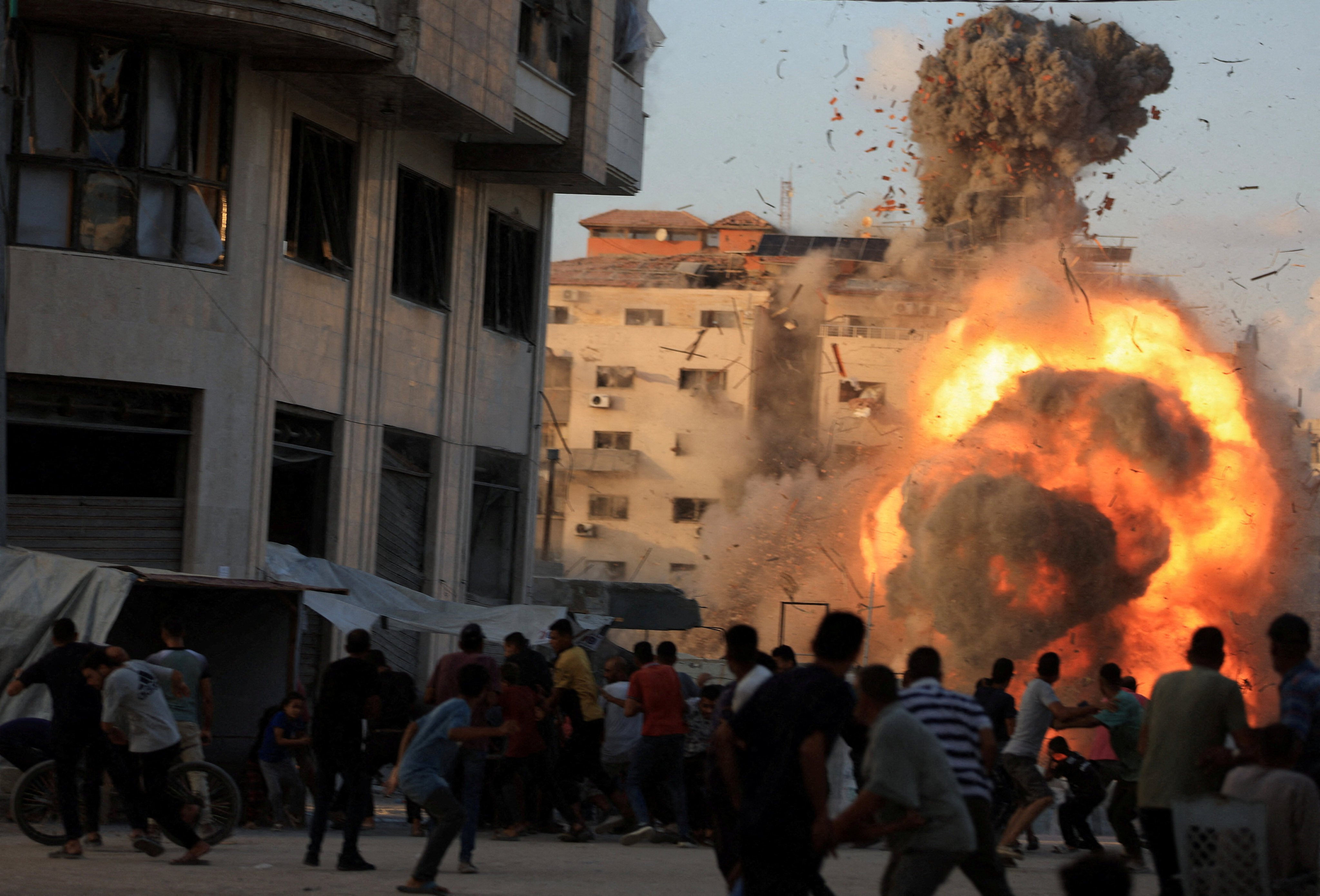 Palestinians react, as smoke and flames rise while a residential building collapses after an Israeli air strike in Gaza City on Sunday. Photo: Reuters