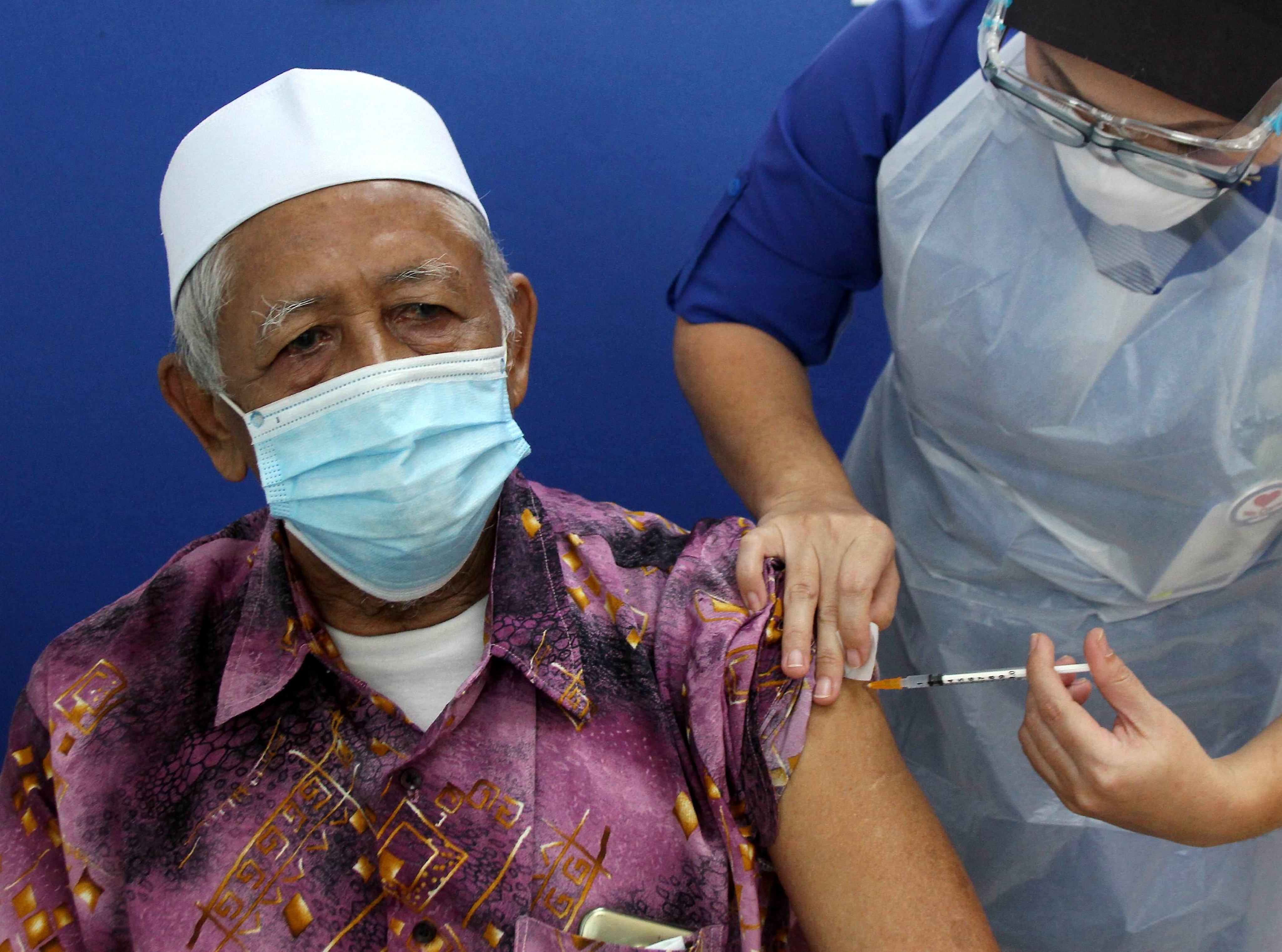 An elderly man receives a dose of a COVID-19 vaccine at a local hospital. A Malaysian lawmaker says many high-income Malaysians have fallen victim to “unregulated and irresponsible marketing” by insurers. Photo: Bernama