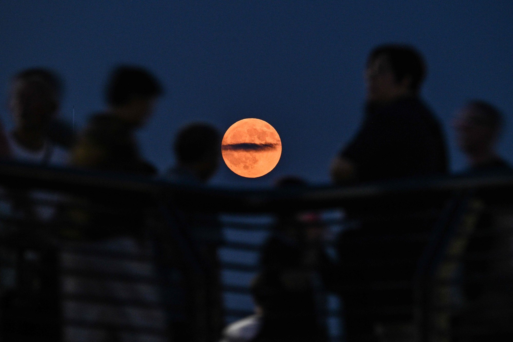 People on the Bund promenade along the Huangpu river as a “Blood Moon” rises above the night sky during a total lunar eclipse in Shanghai on Sunday. Photo: AFP