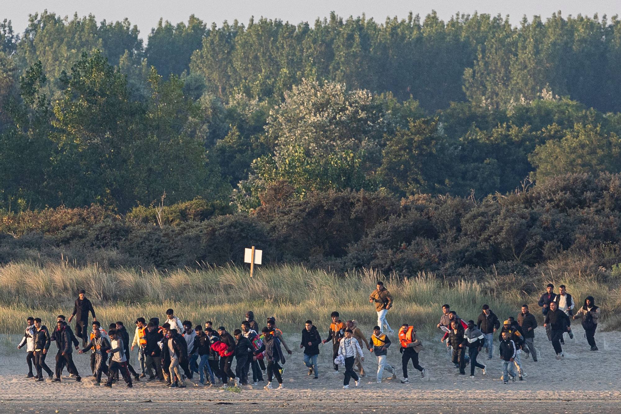 Migrants run on the beach to wait for a smuggler’s boat to attempt crossing the English Channel off the beach of Gravelines, northern France on August 11. Photo: AFP