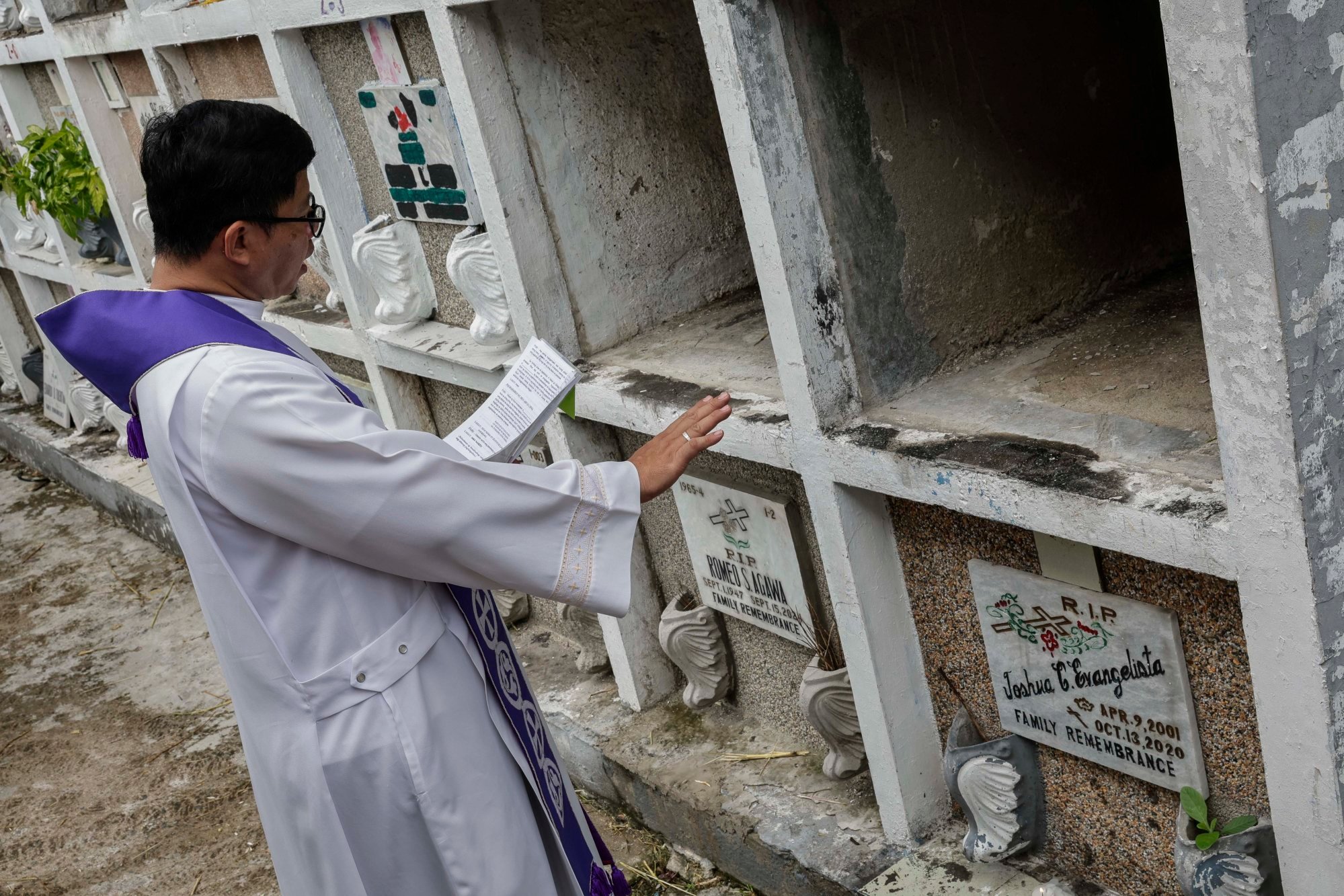A Catholic priest recites a prayer at a temporary burial site of a victim of alleged extra-judicial killing at a cemetery in Metro Manila last month. Photo: EPA