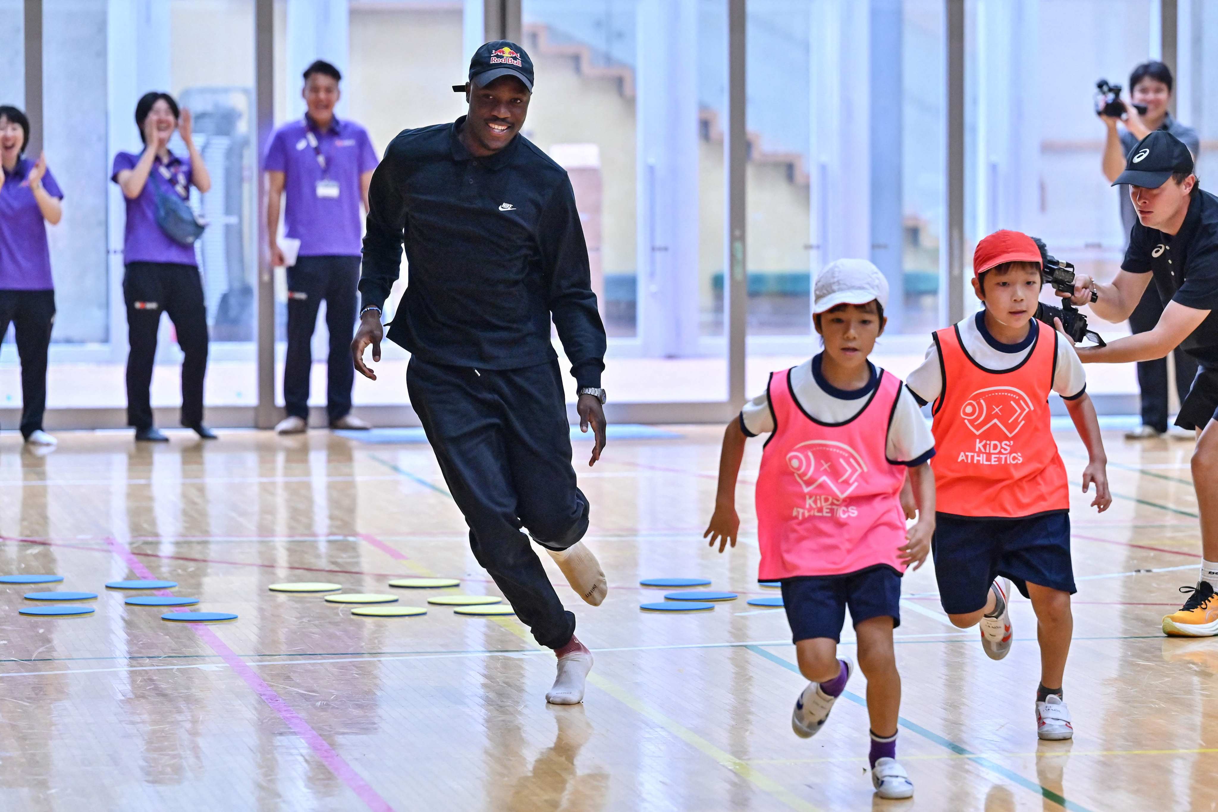Olympic 200m champion Letsile Tebogo runs with children around a course during a visit to a primary school gymnasium on Tuesday before the start of the World Athletics Championships in Tokyo. Photo: AFP