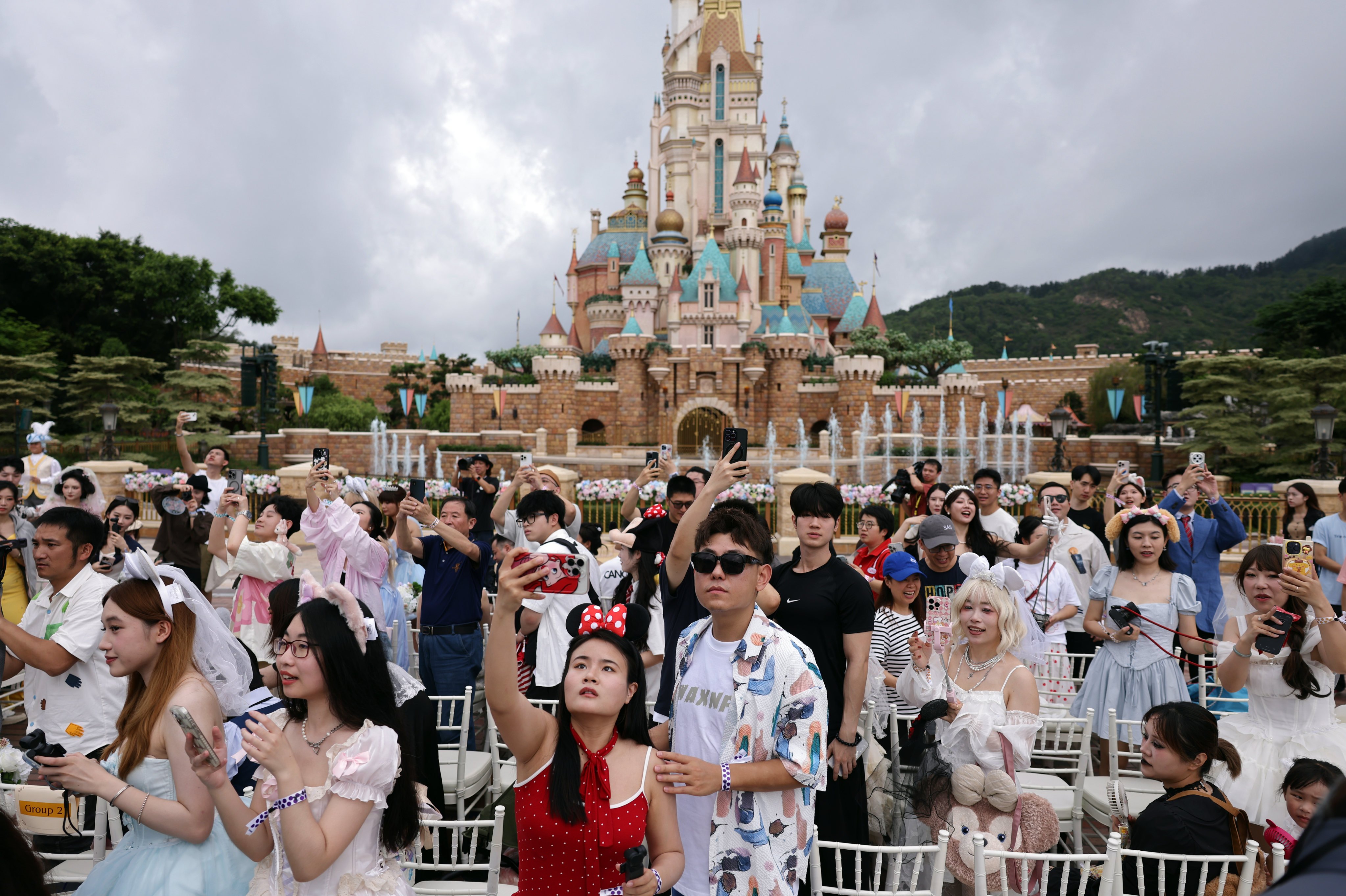 Mainland couples celebrate Chinese Valentine’s Day with Disneyland mascots in front of the Castle of Magical Dreams at Hong Kong Disneyland on May 20. Photo: Nora Tam