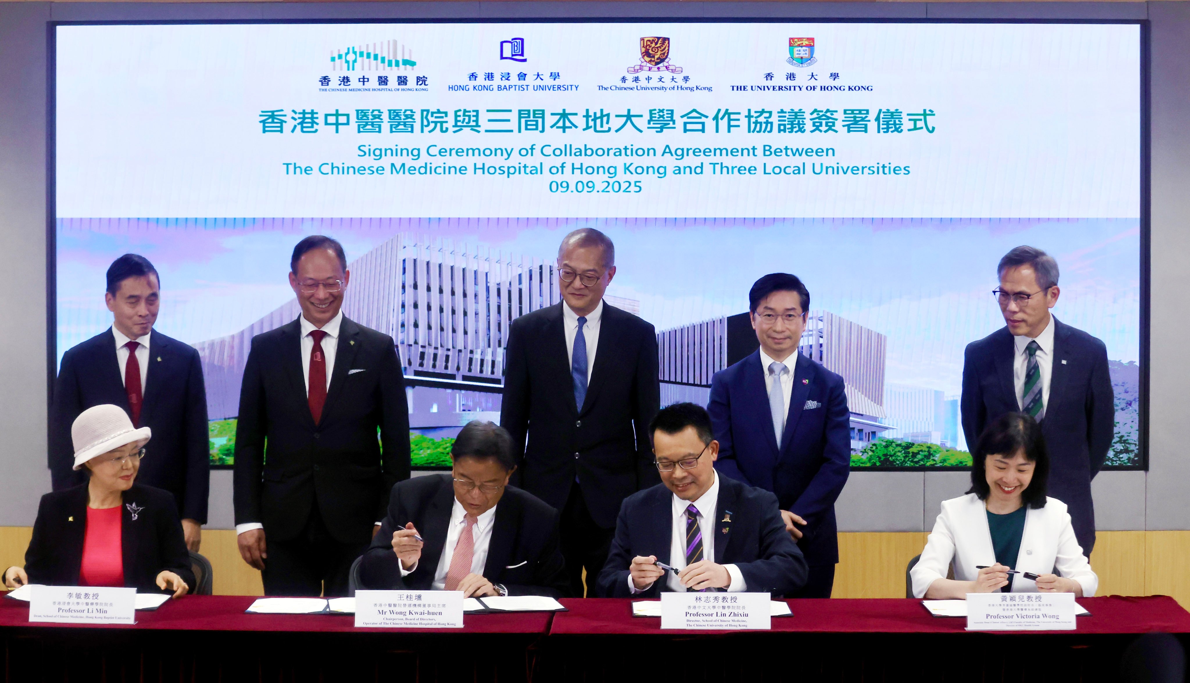 Representatives of three local universities sign agreements with the new hospital as health chief Lo Chung-mau (standing, centre) looks on. Photo: Jonathan Wong