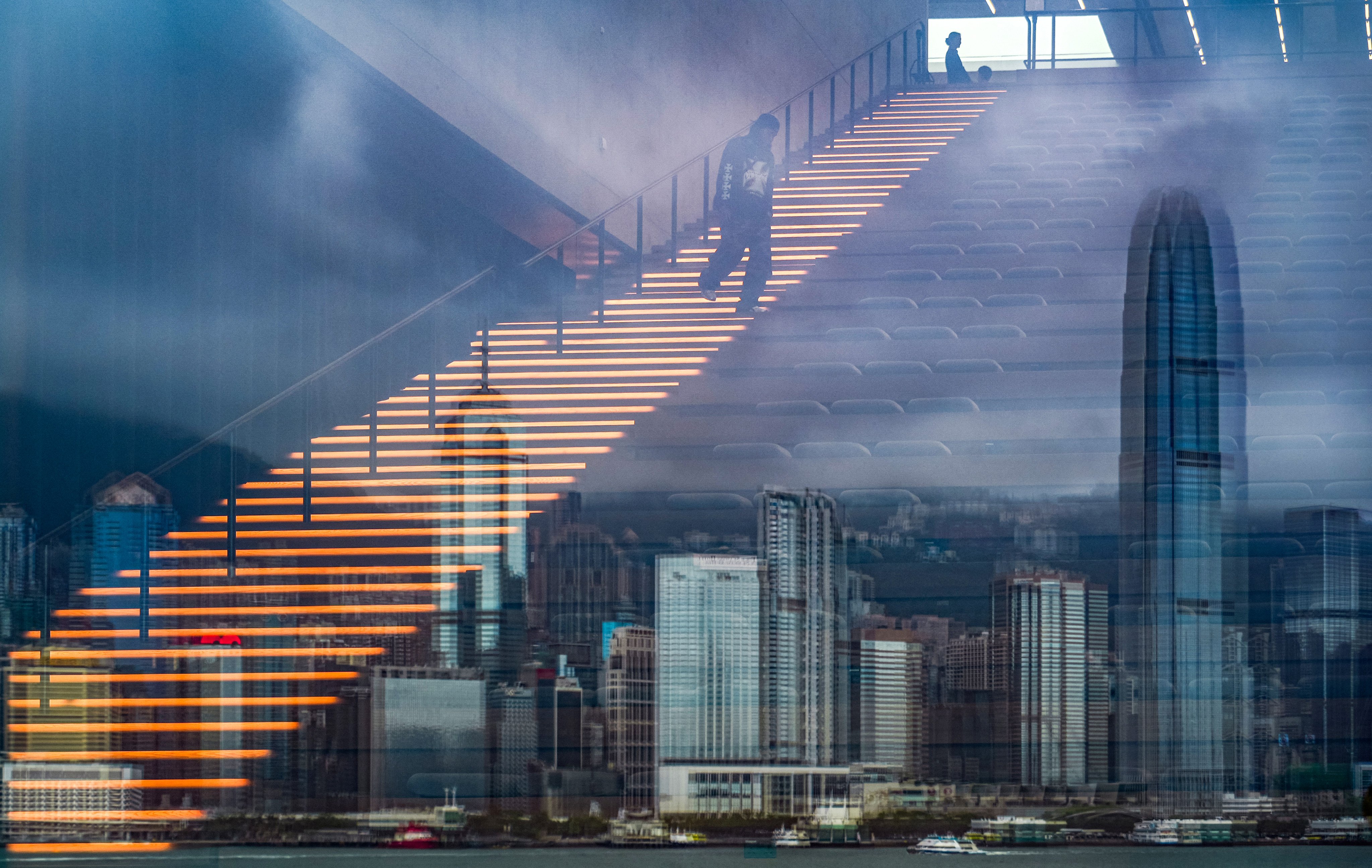 A man walks down an illuminated staircase at M+ in West Kowloon as the Hong Kong skyline is reflected in glass. For all its marquee exhibitions, the West Kowloon Cultural District has yet to cement itself as a must-visit for both locals and tourists. Photo: Eugene Lee