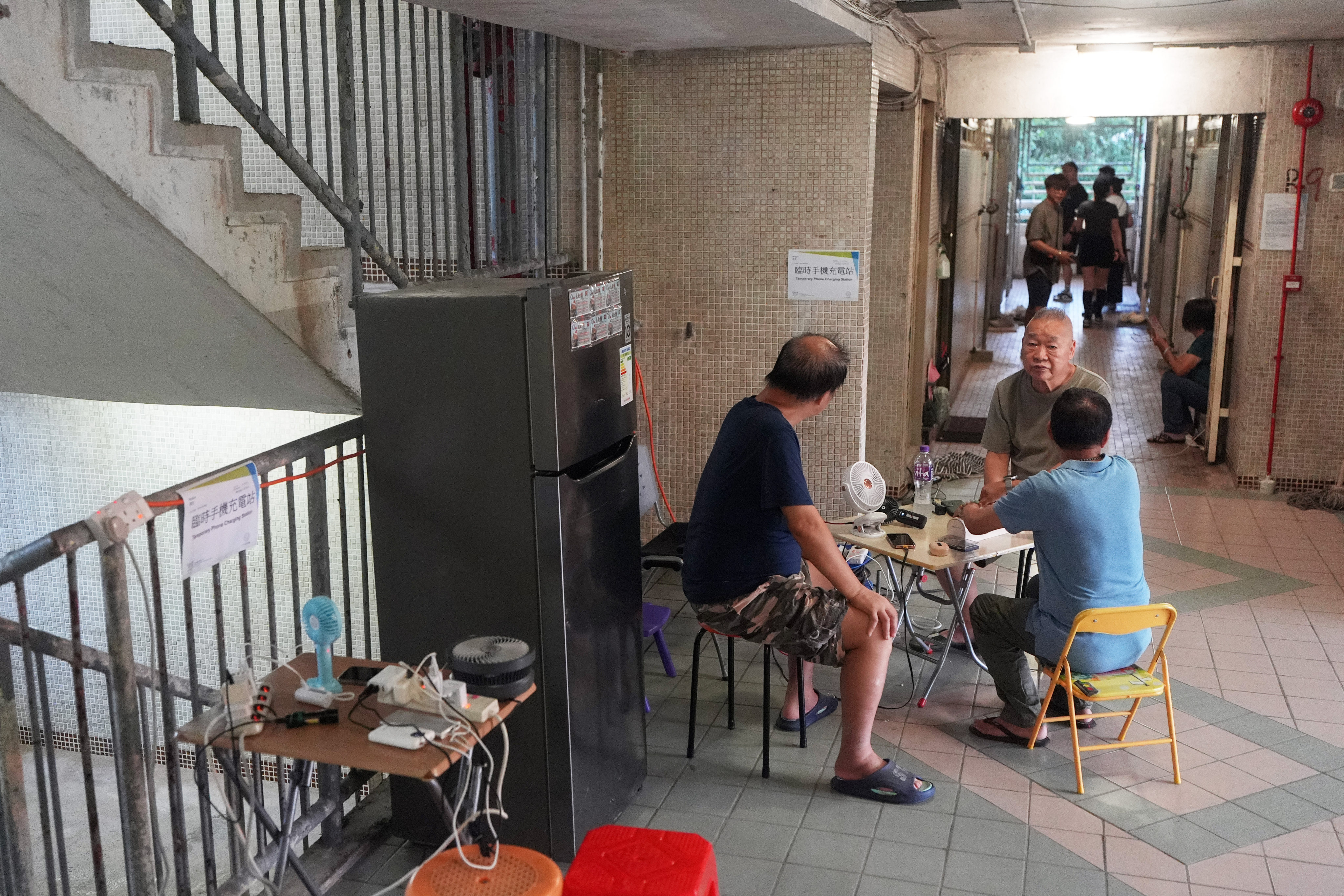 Residents of Tin Ming House use a temporary power supply in the lift lobby on Sunday evening. Photo: Eugene Lee