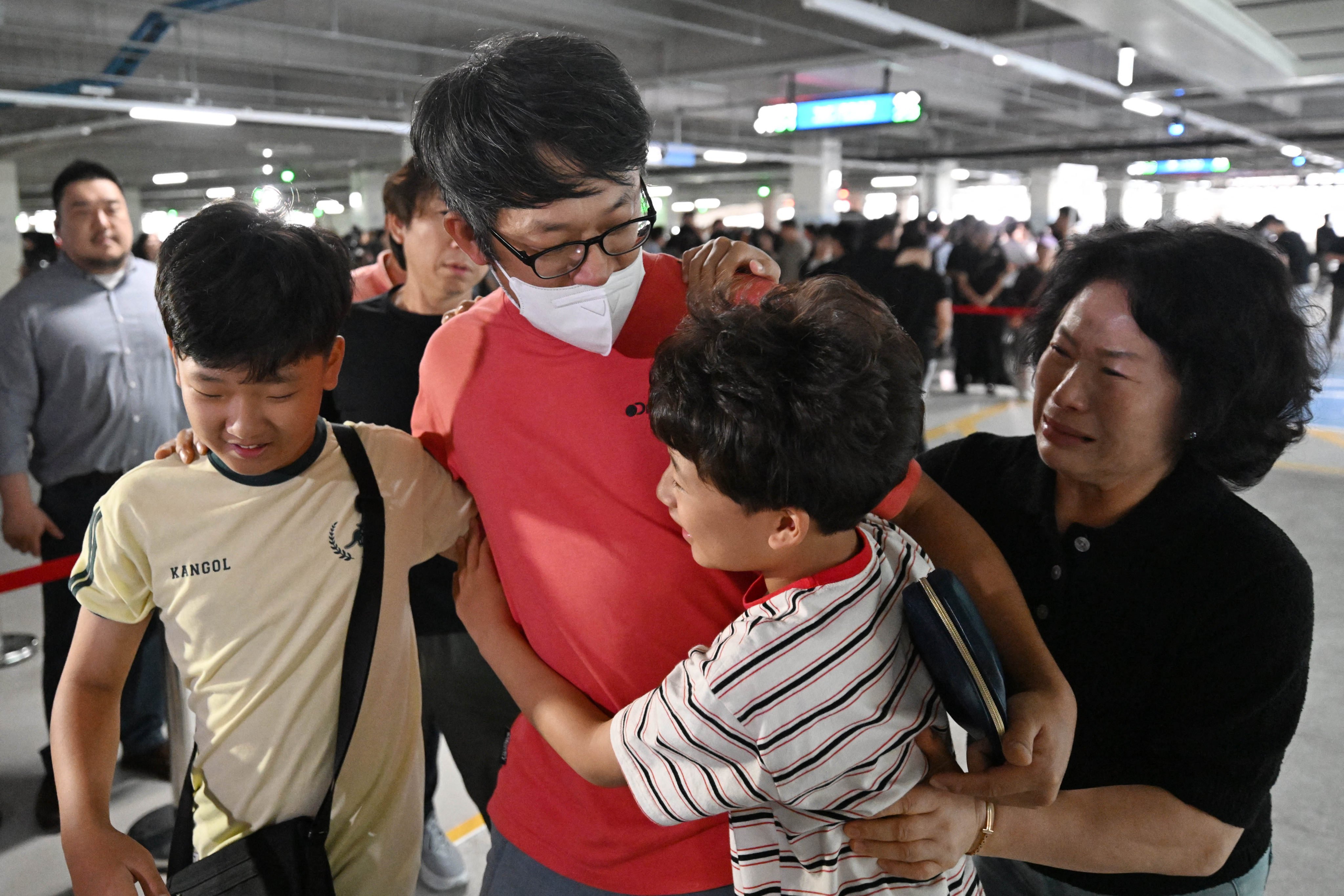 A South Korean worker (second left), who was detained in a US immigration raid, is welcomed by family members at Incheon airport on Friday. Photo: Yonhap/AFP