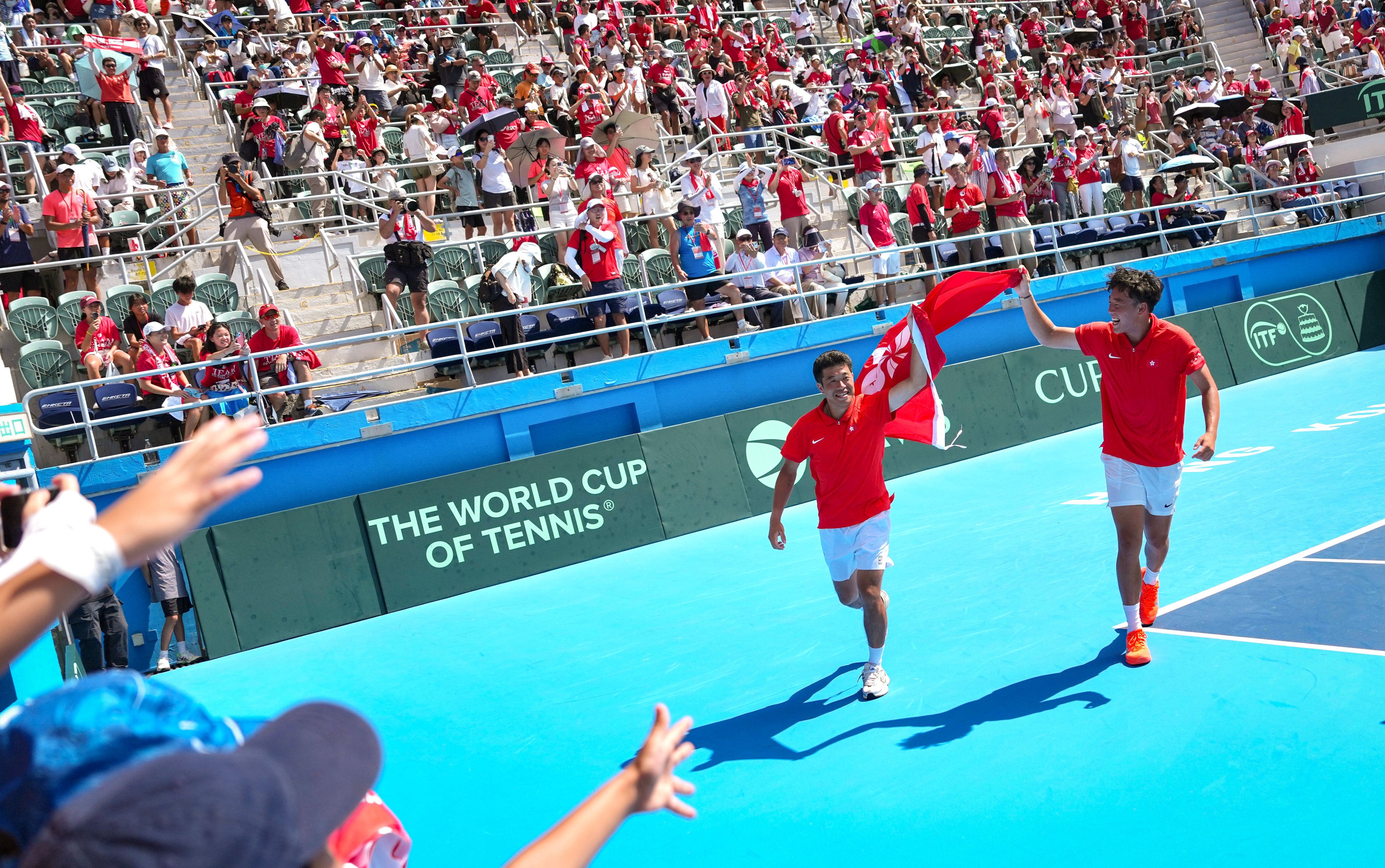 Coleman Wong (right) and Wong Chun-hun walk around Victoria Park Tennis Stadium’s centre court with the Hong Kong flag after their doubles victory. Photo: Karma Lo