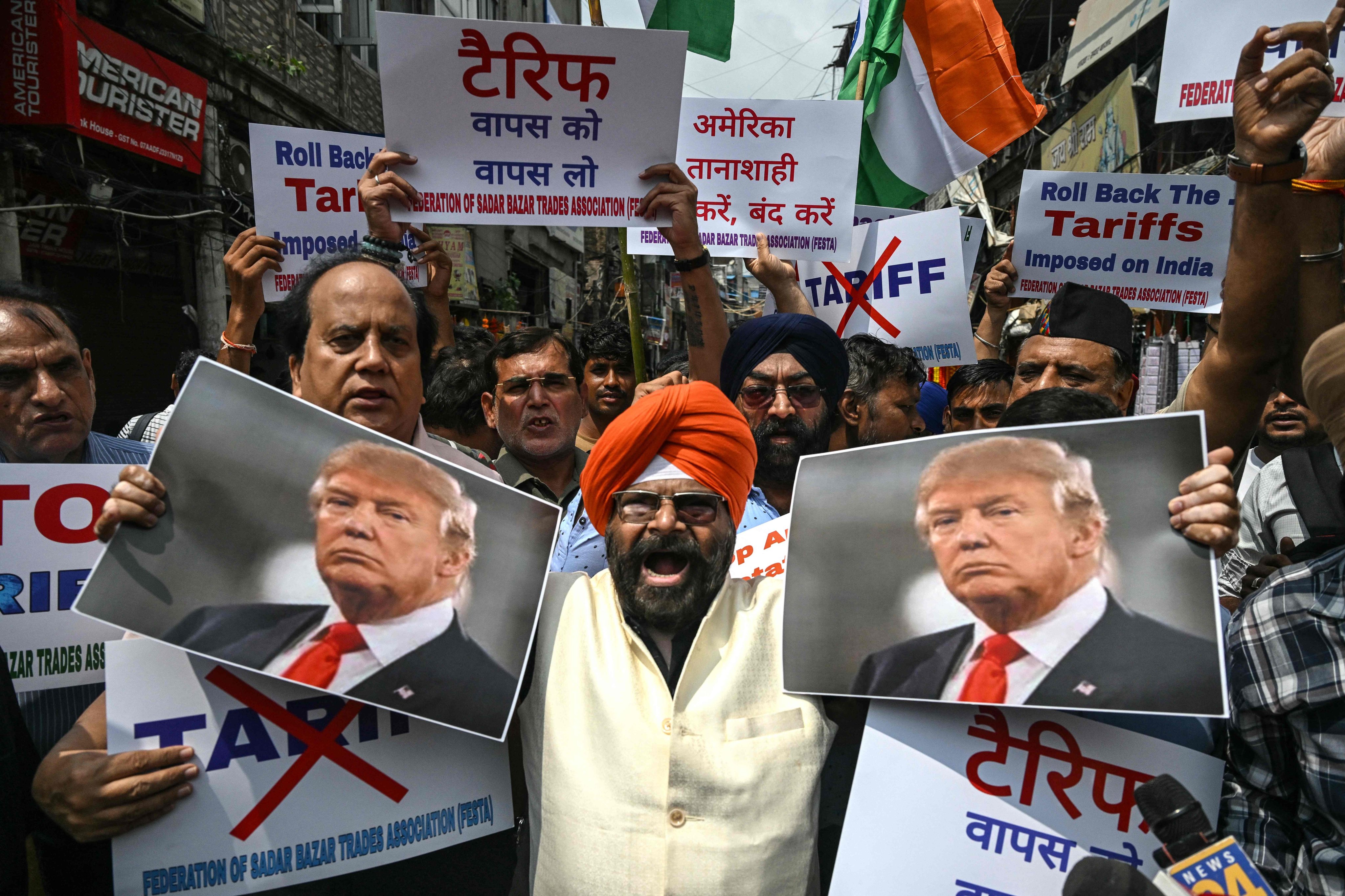 Members of a trade association holding posters of US President Donald Trump and other placards protest against the recent tariff hikes imposed by the US on India, in New Delhi on August 30. Photo: AFP