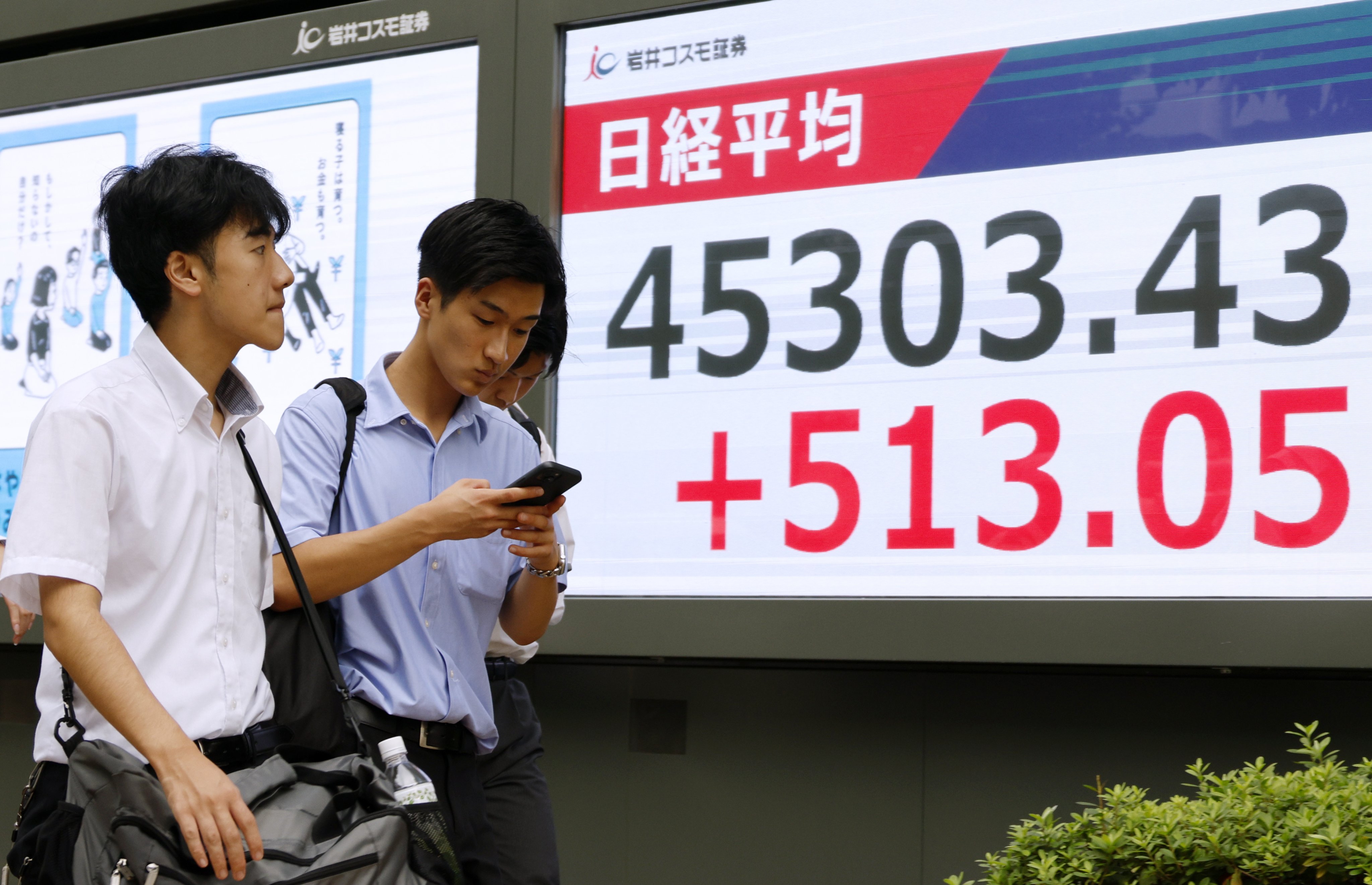Pedestrians walk past a stock market indicator board in Tokyo on September 18 as the index soars following the US Federal Reserve’s decision to cut interest rates. Photo: EPA